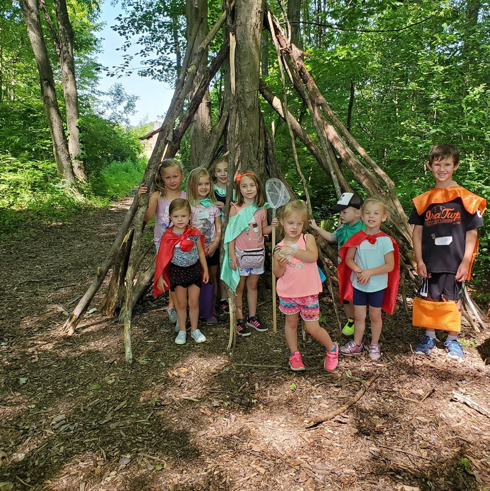 A group of children are posing for a picture in the woods.