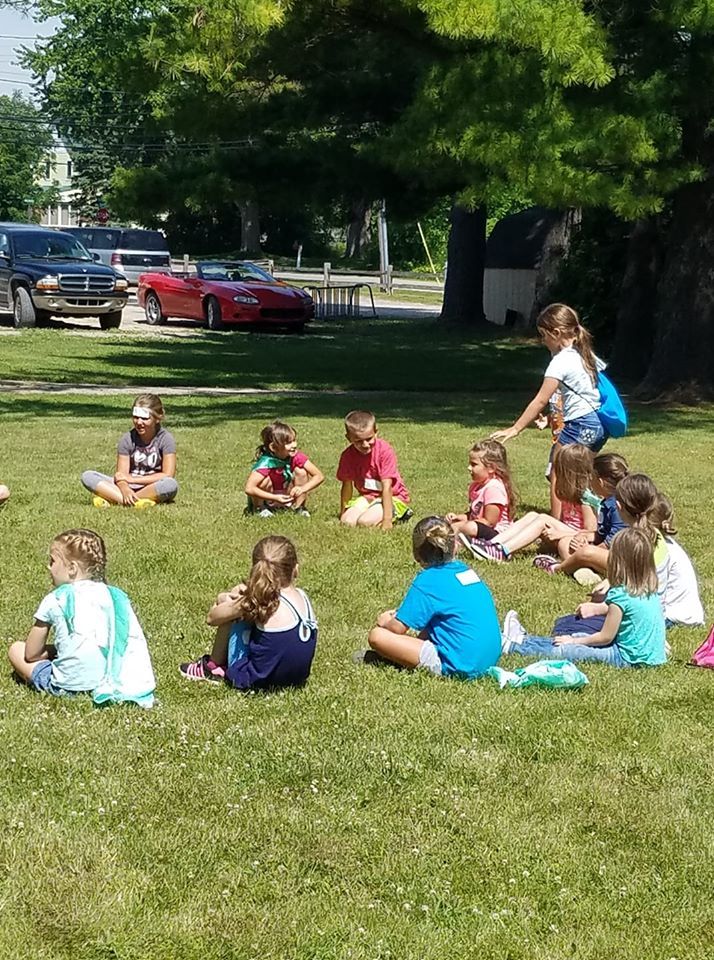 A group of children playing duck duck goose.
