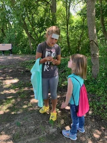A woman and a little girl are standing next to each other in the woods.
