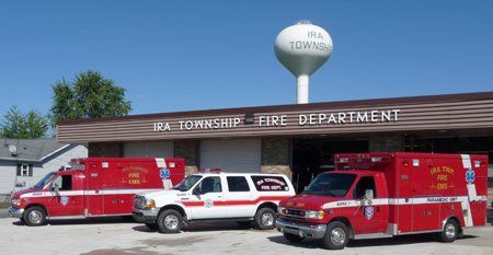 Three fire trucks are parked in front of a fire department building.