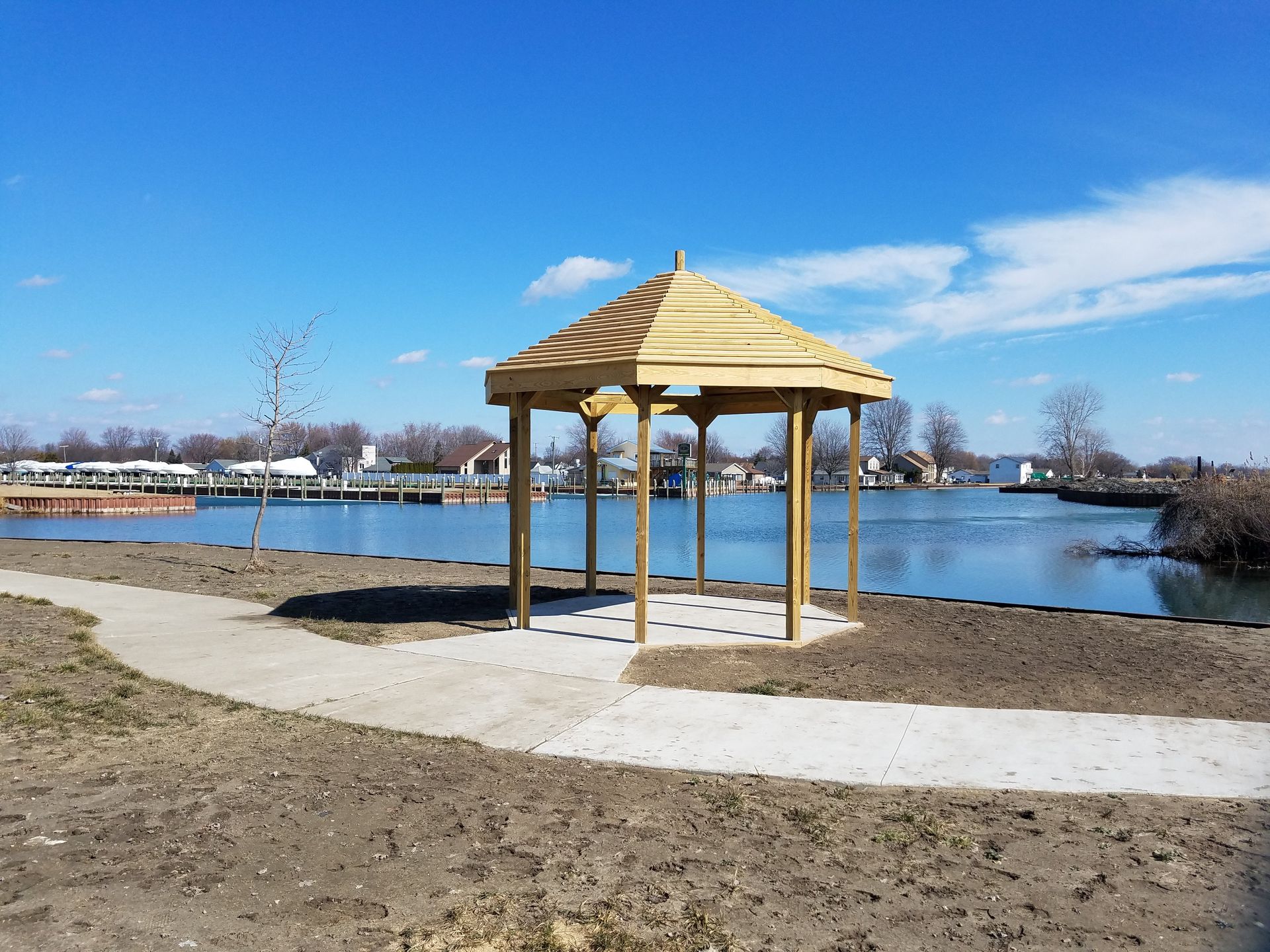 A wooden gazebo sits on the shore of a lake.