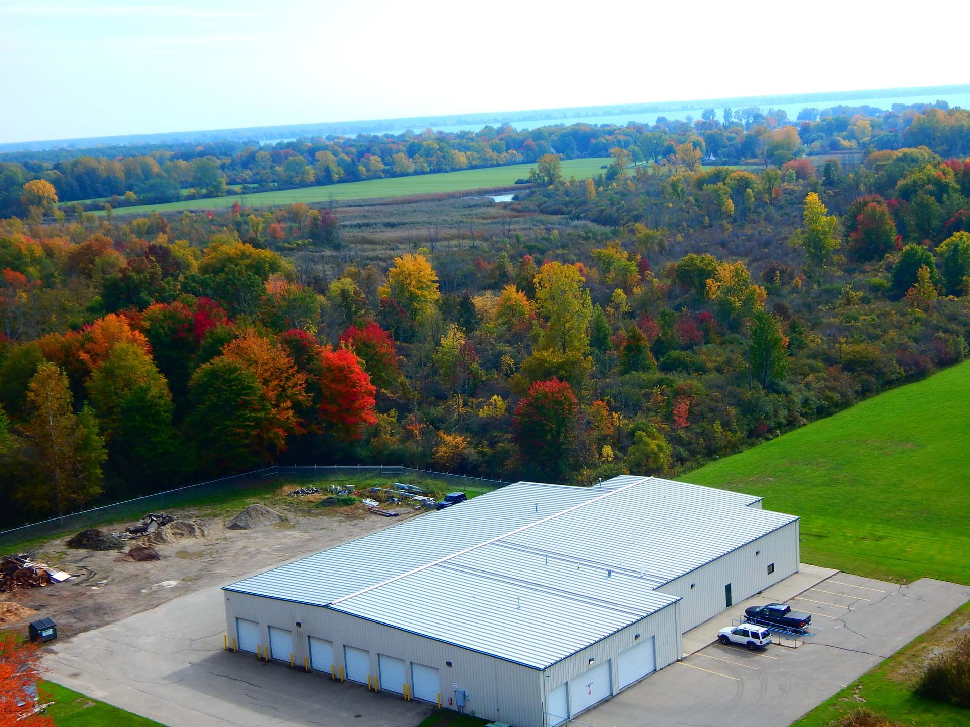 An aerial view of a building in a field with trees in the background.