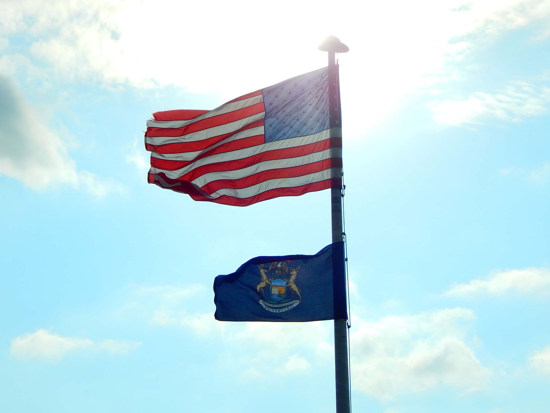 Two flags on a pole one of which has the state of Michigan on it.