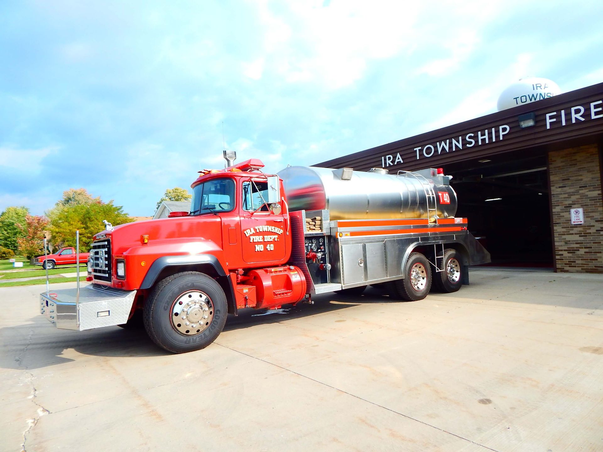 A red truck is parked in front of a fire station.