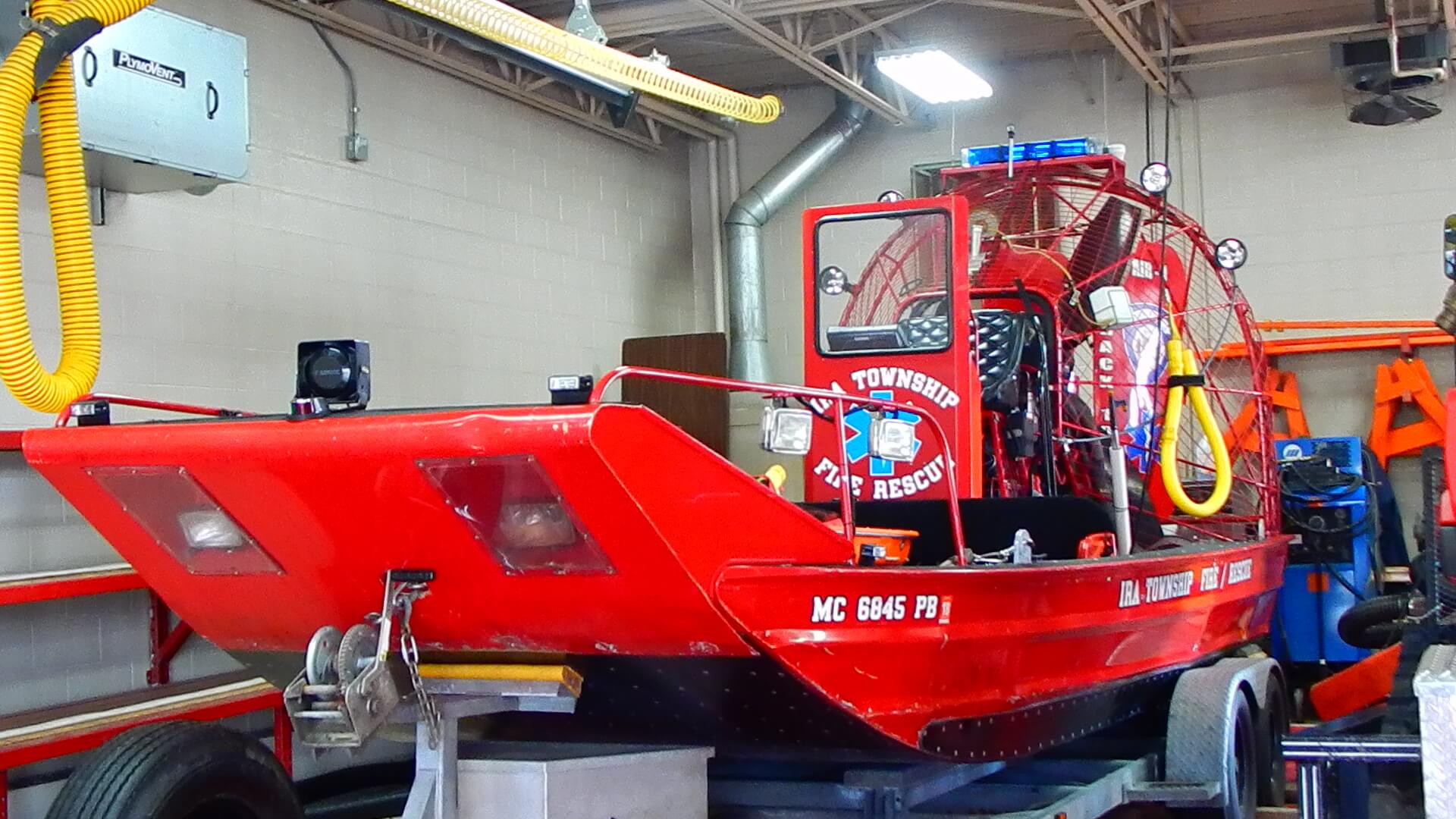 A red boat in a garage with Ira Township written on the side.