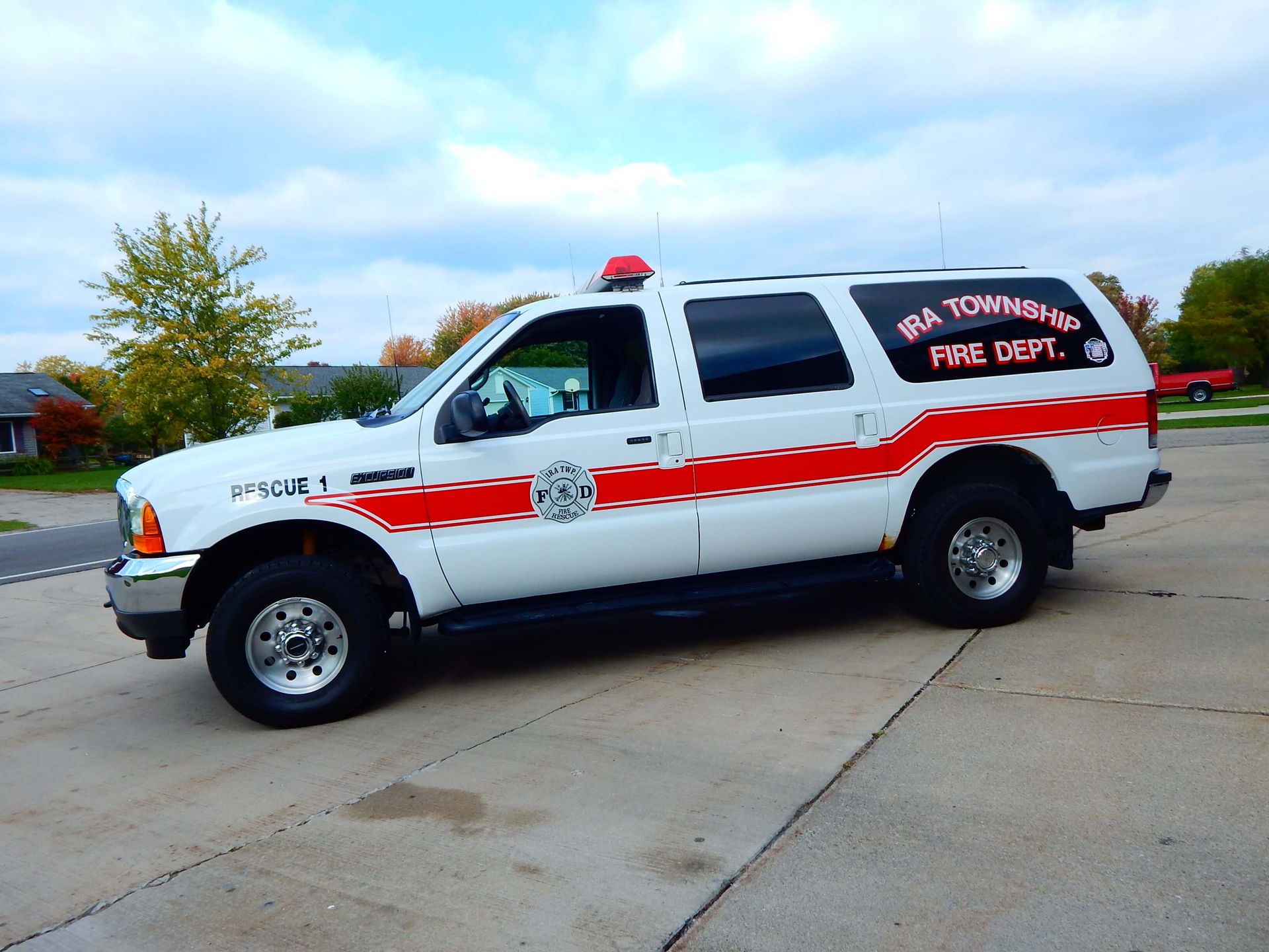 A white rescue vehicle is parked in front of a building that says Ira Township Fire Department.
