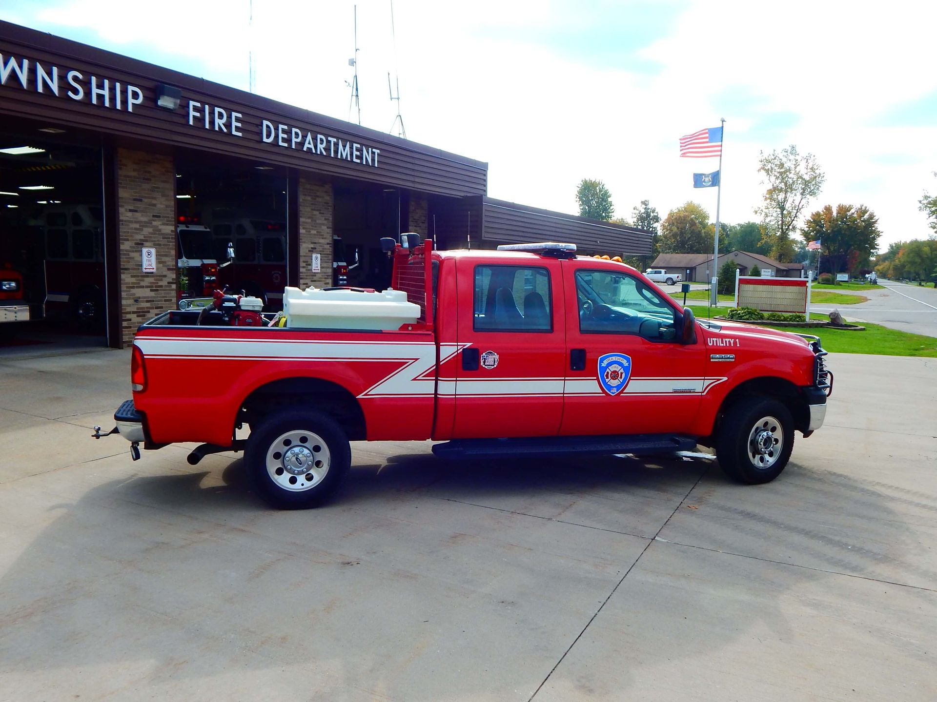 A red truck is parked in front of a fire department building.