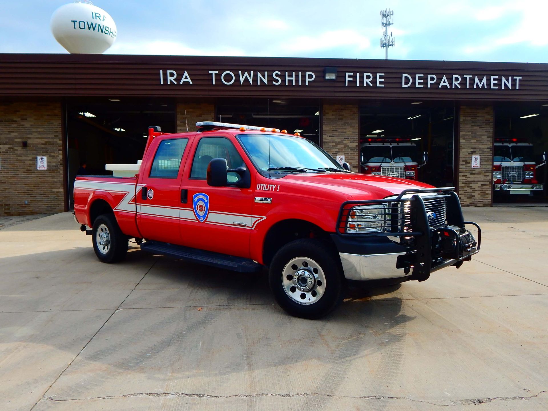 A red truck is parked in front of the Ira Township Fire Department.