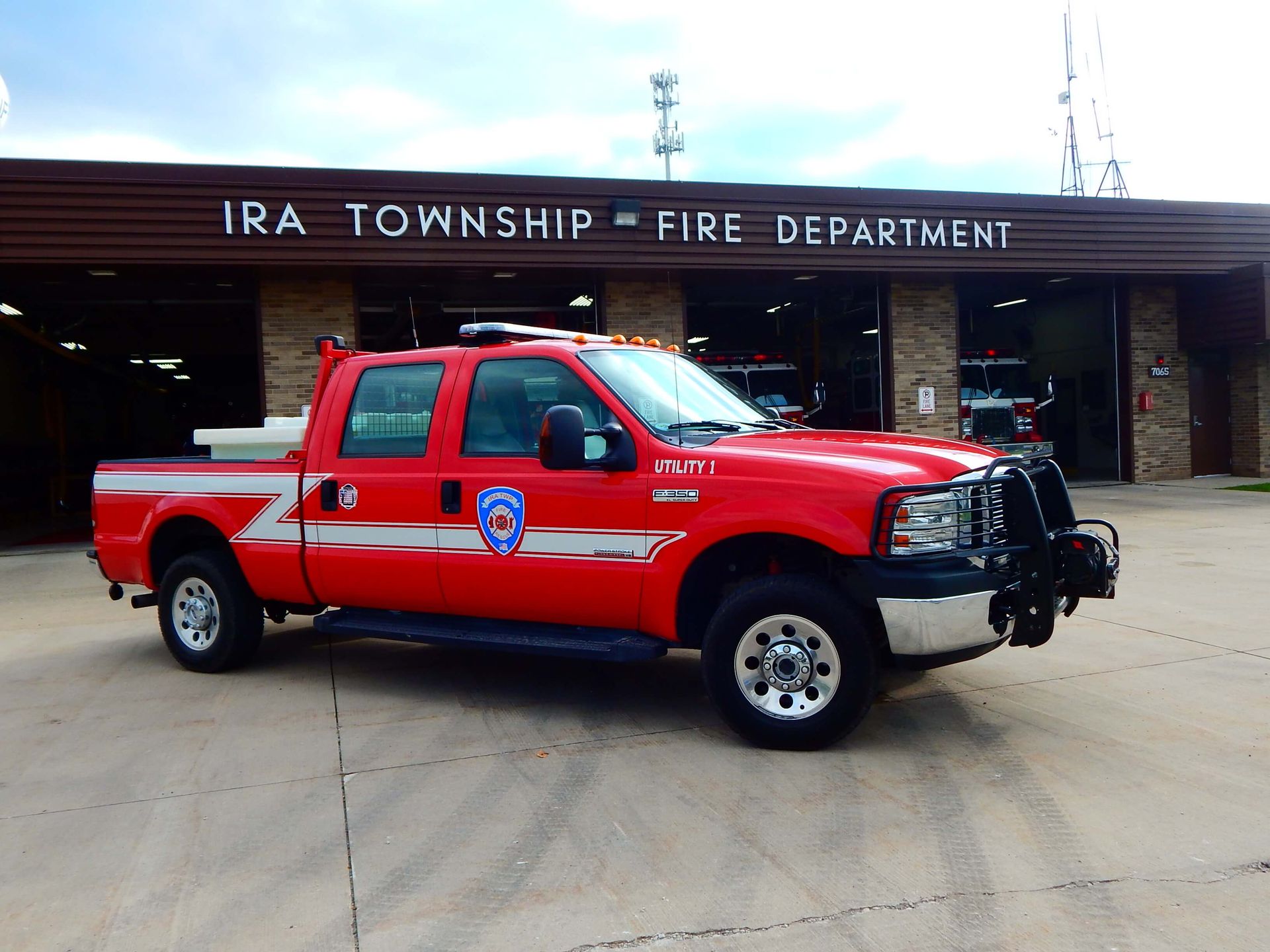 A red truck is parked in front of the Ira Township Fire Department.