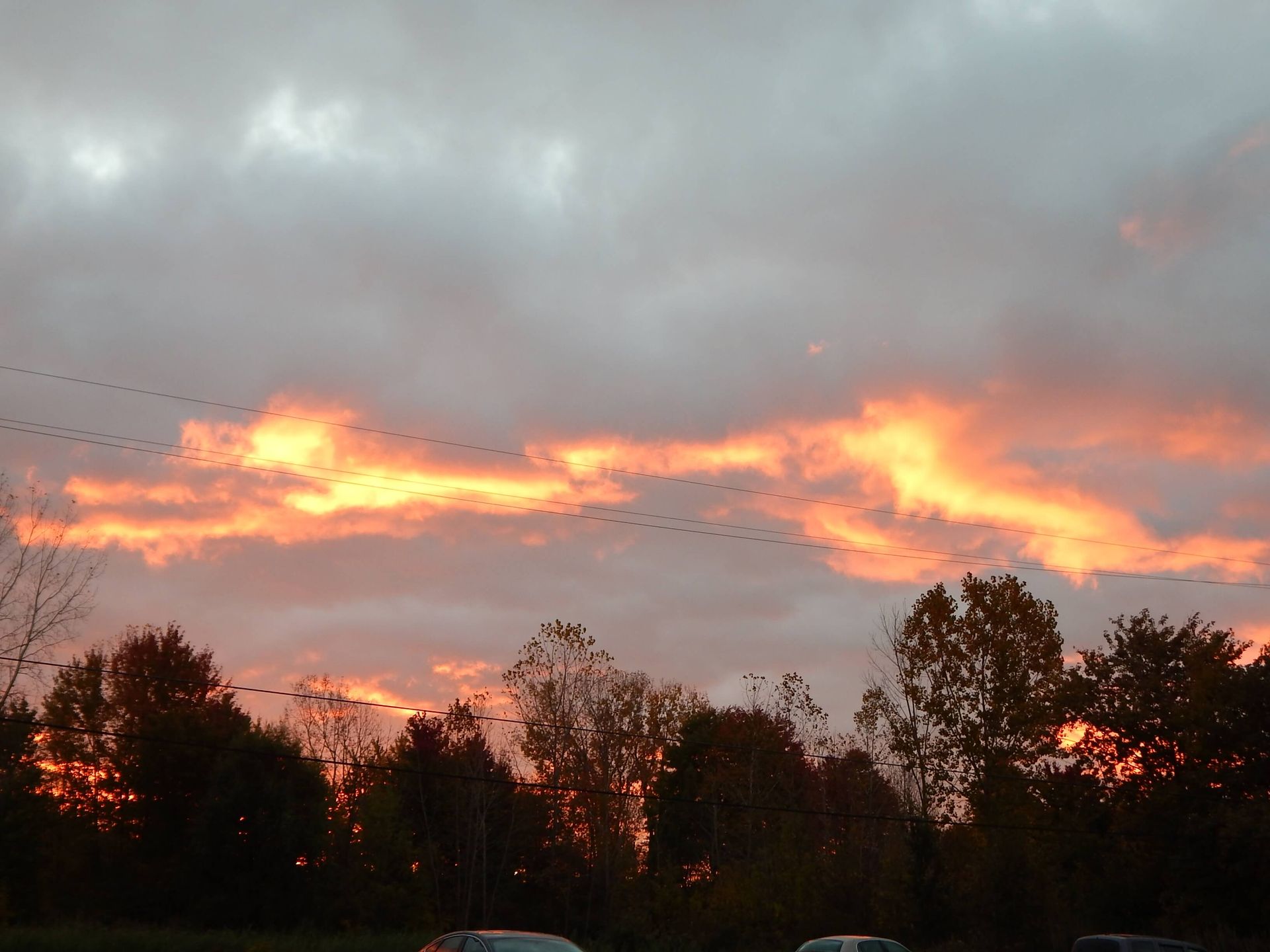 A sunset with a lot of clouds and trees in the foreground.