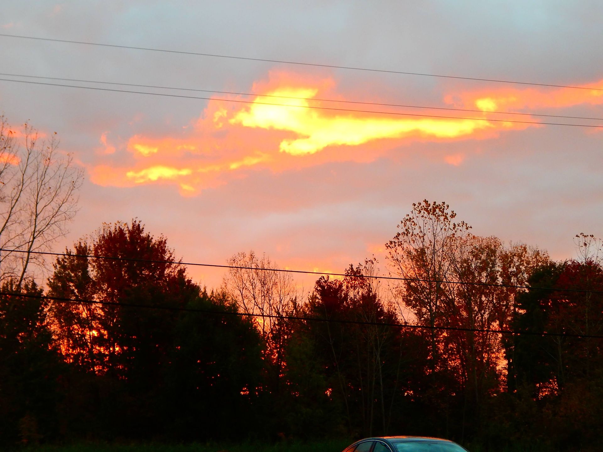 A car is parked in front of a sunset sky