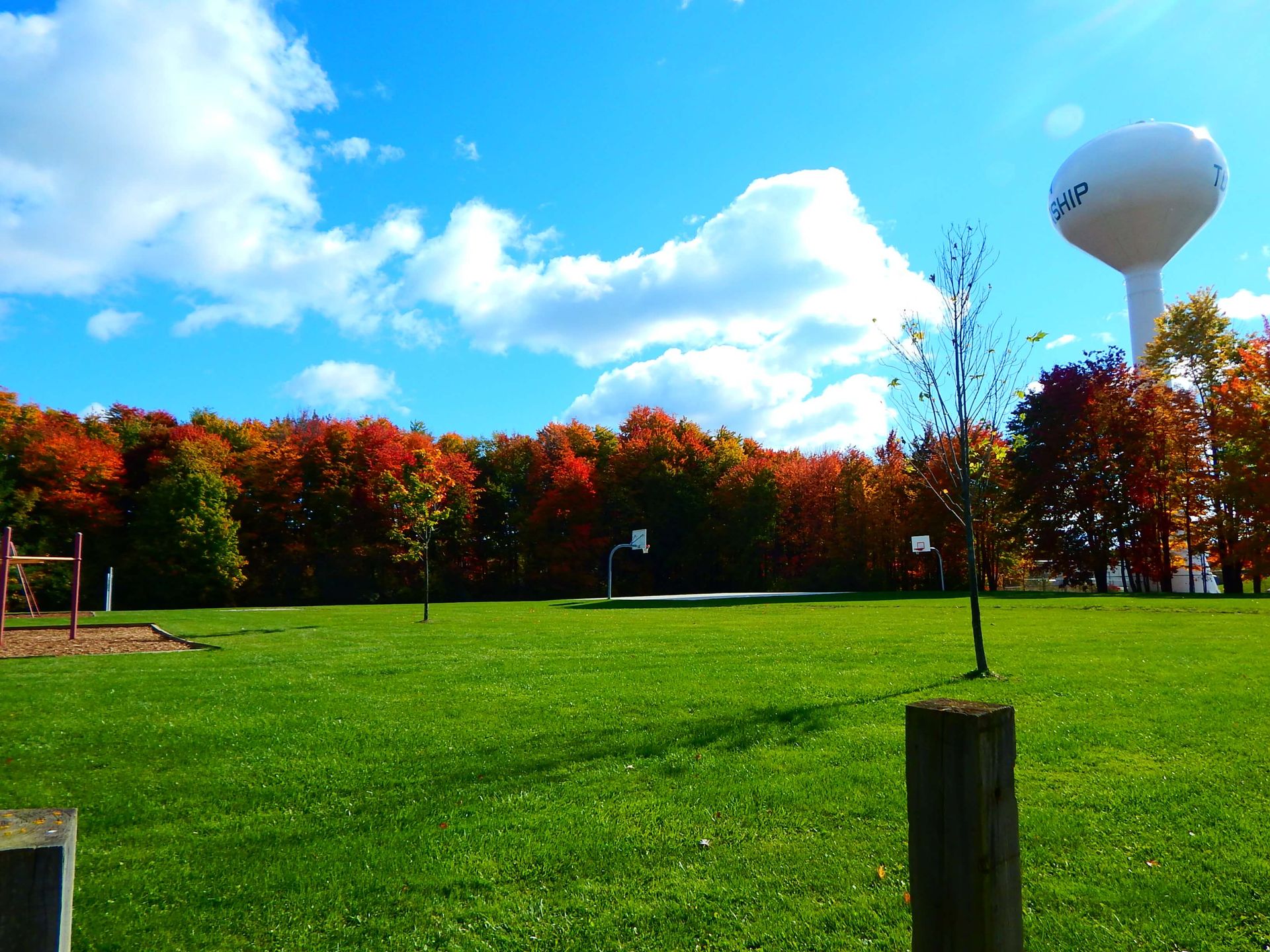 A water tower in a park with trees in the background.