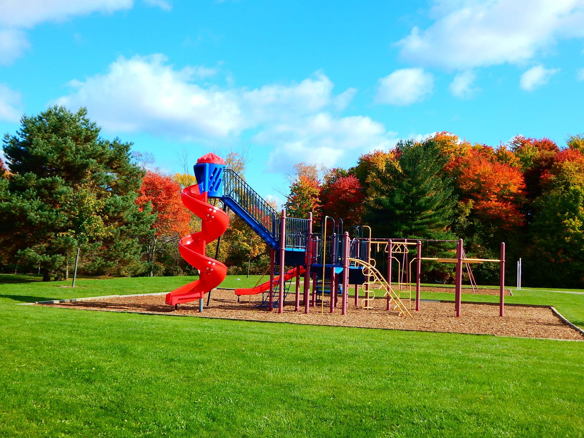 A playground with a red slide and a blue slide.