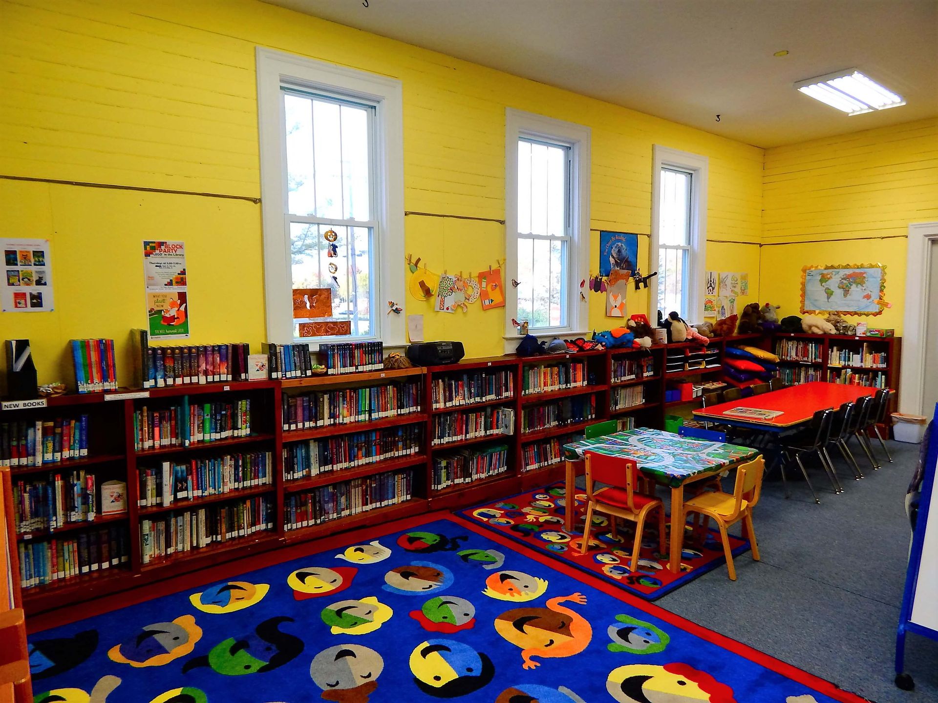 A library with yellow walls and a blue rug.