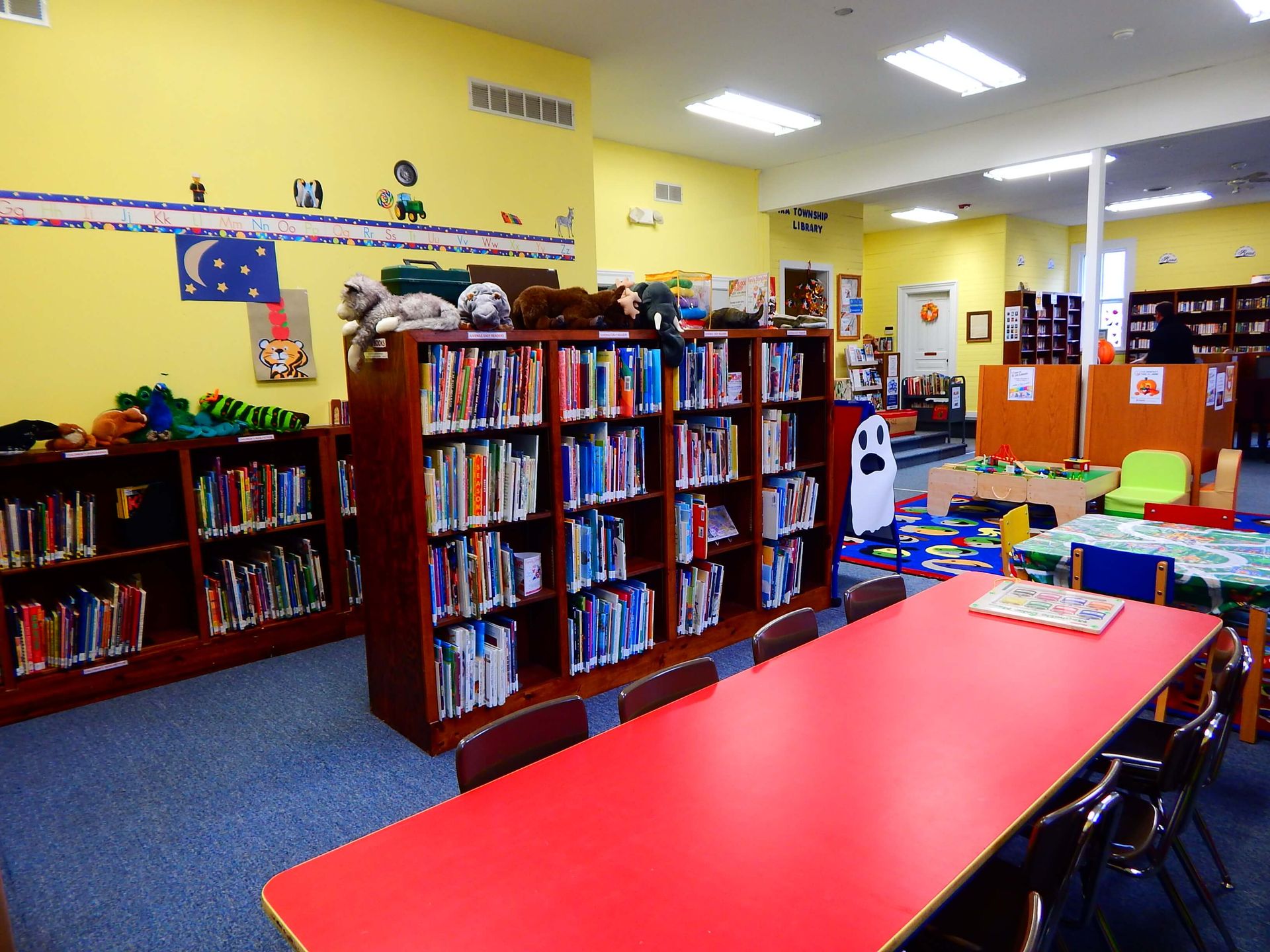 A library with lots of books and a red table.