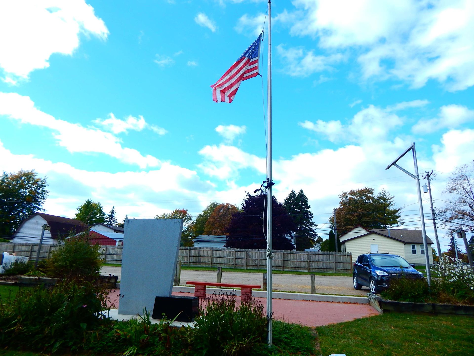 An American flag is flying on a pole in a park.