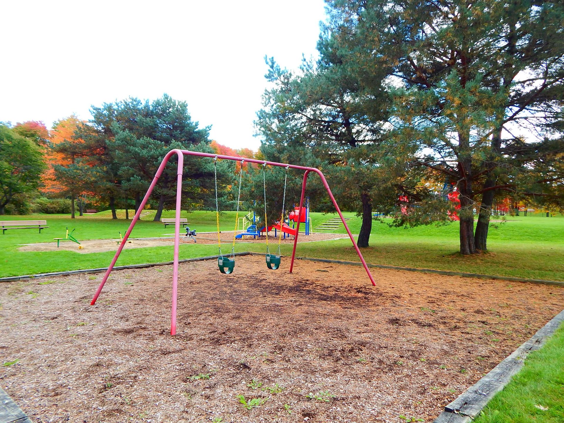 A playground with swings and a slide in a park.