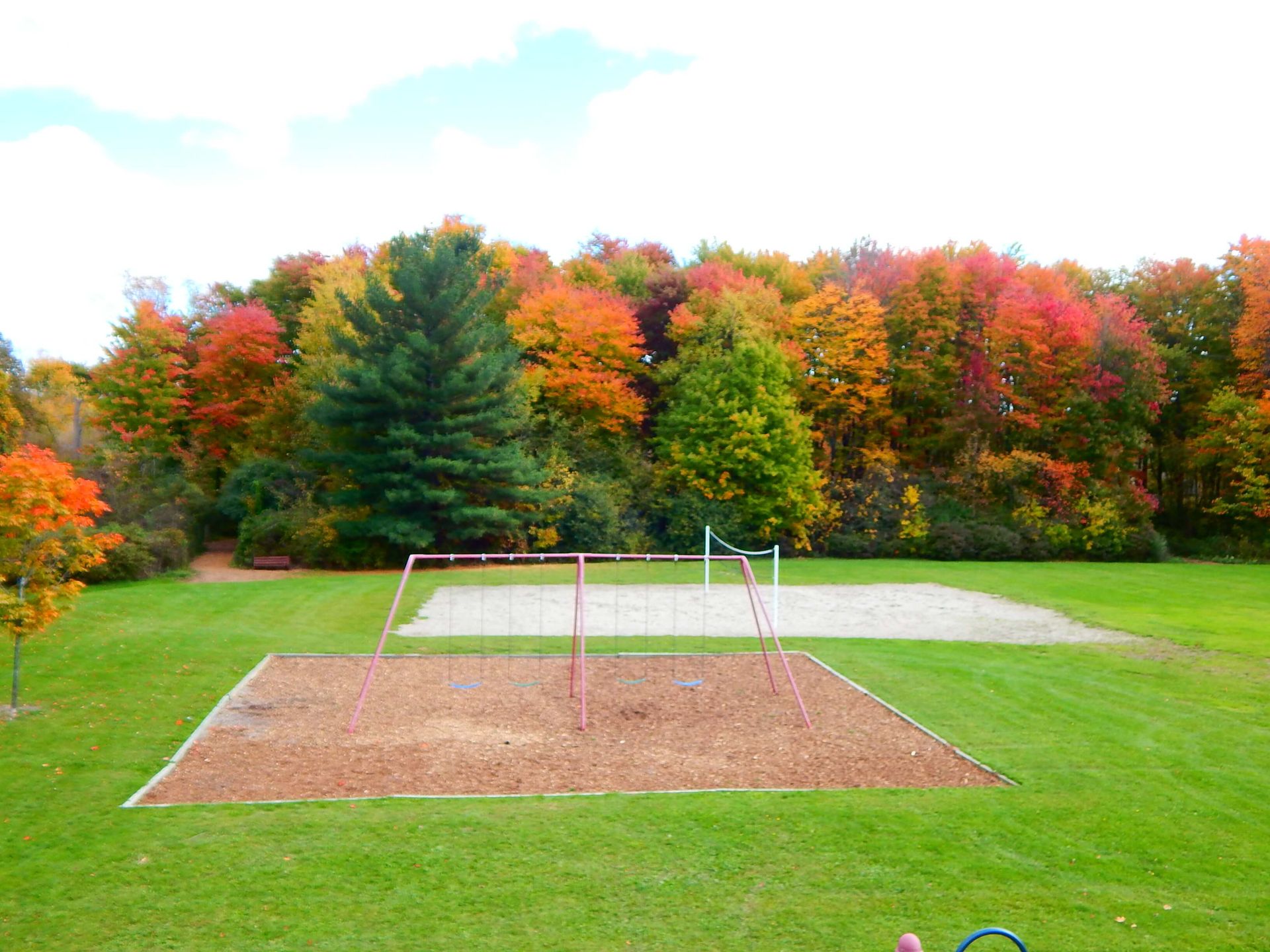 A volleyball court in a park with trees in the background.
