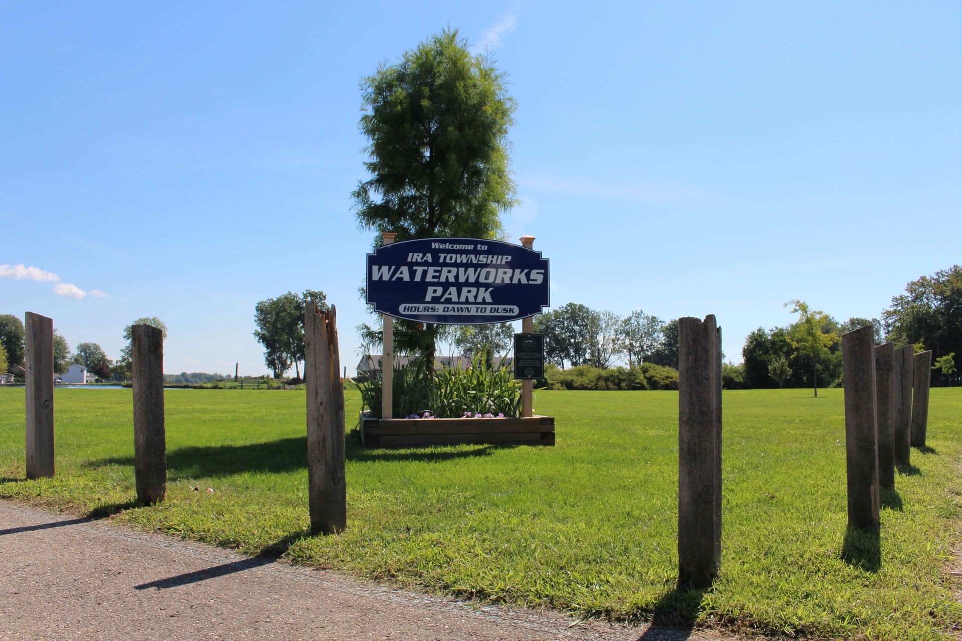 A sign in the middle of a grassy field says Welcome to Ira Township Waterworks Park.