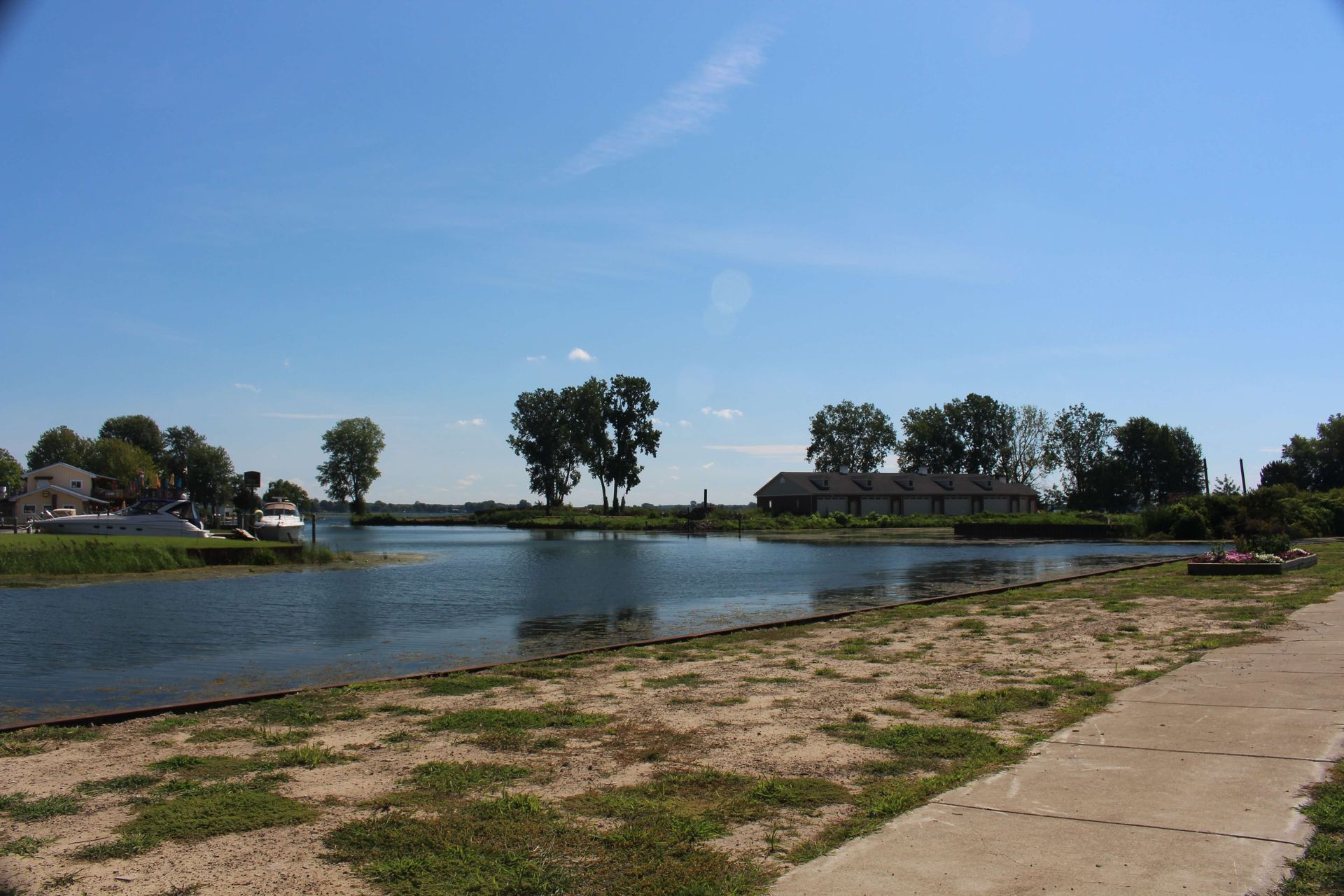 A body of water surrounded by grass and trees on a sunny day.