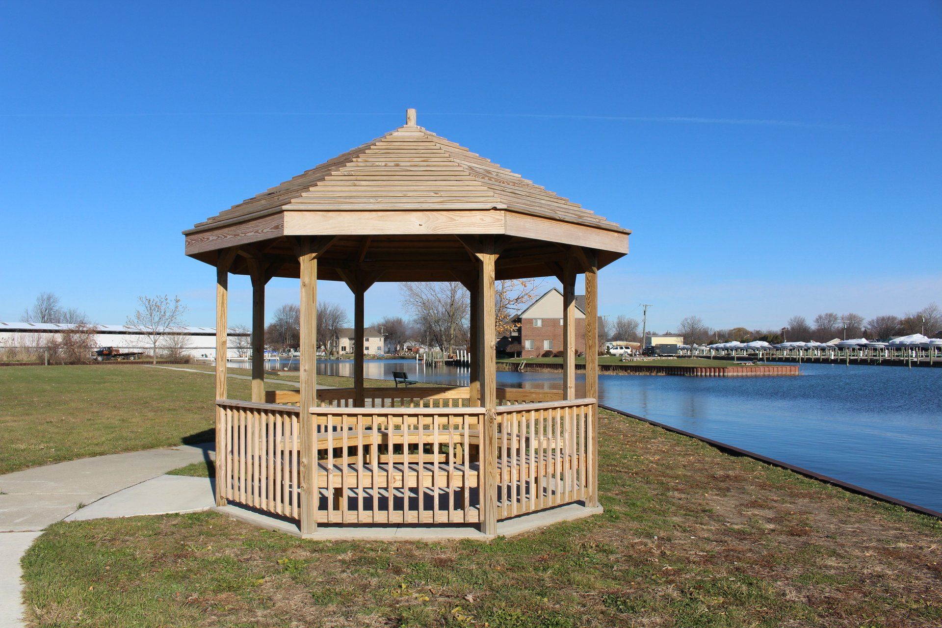 A wooden gazebo sits next to a body of water.