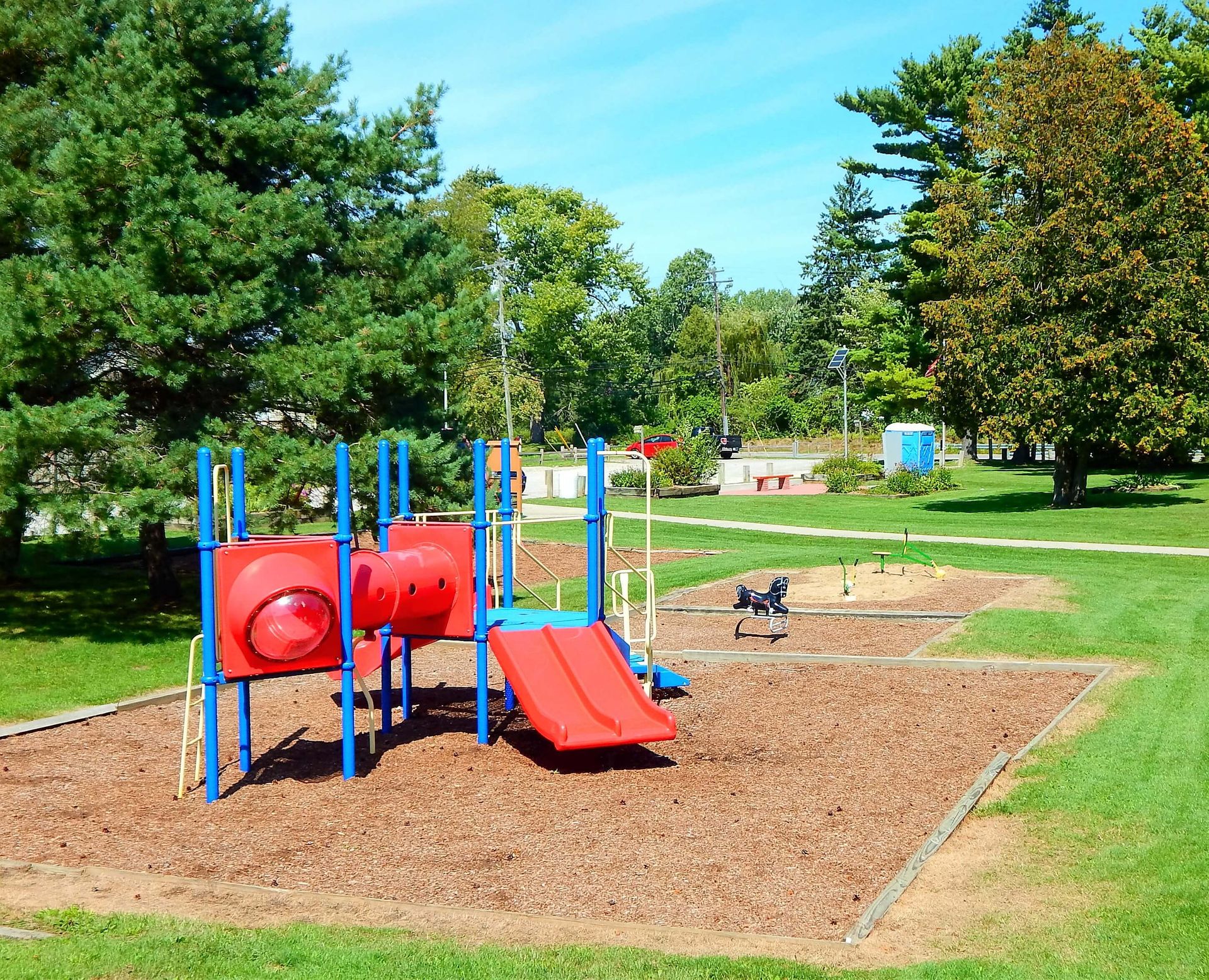 A red and blue playground set in a park.