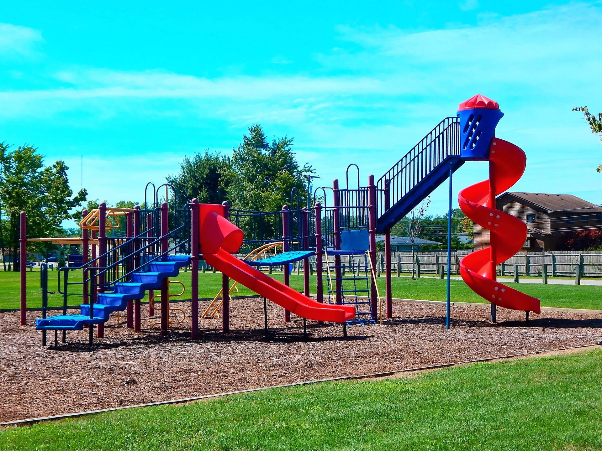 A playground with a red and blue slide and stairs.