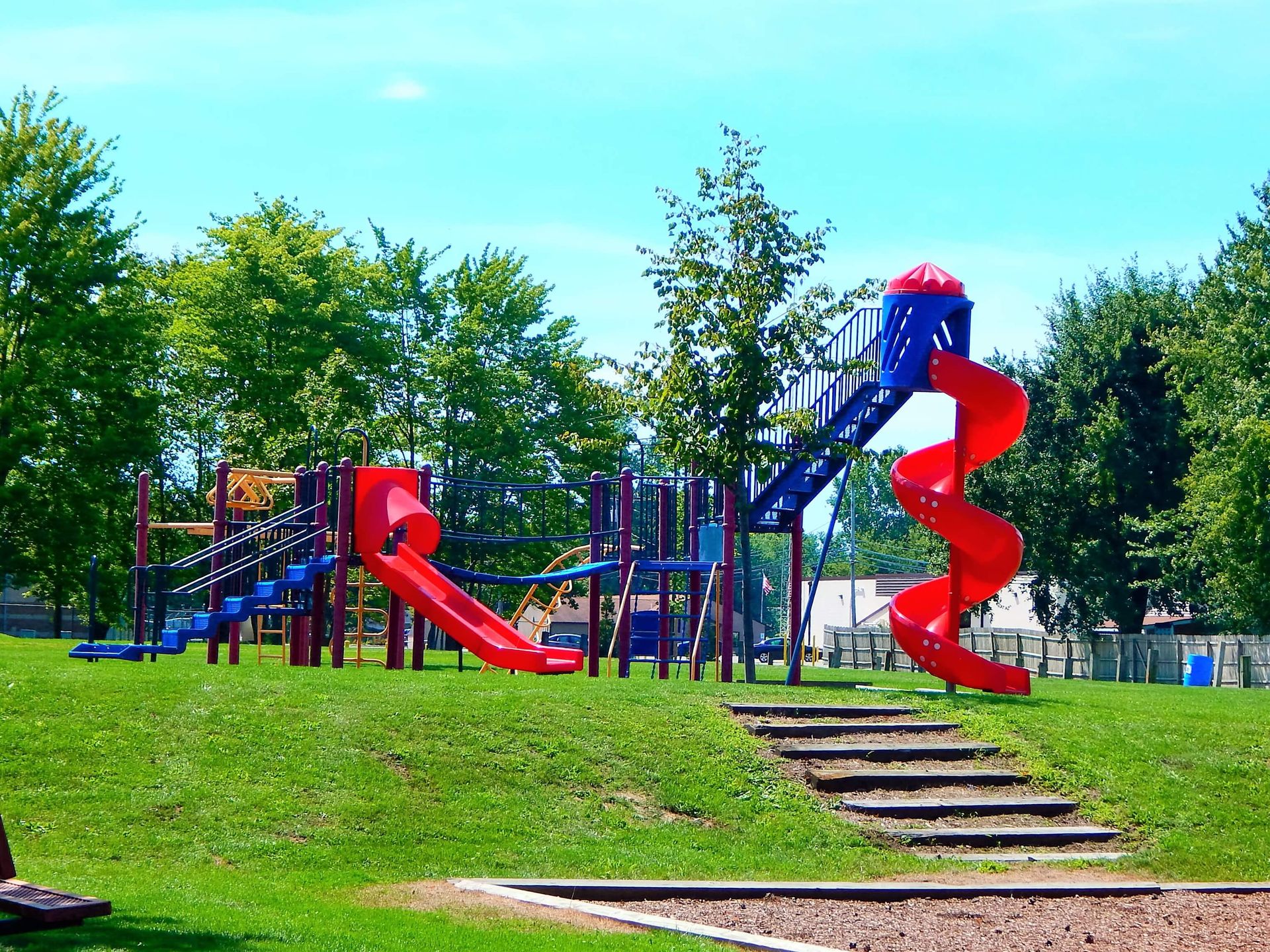 A playground with red and blue slides and stairs
