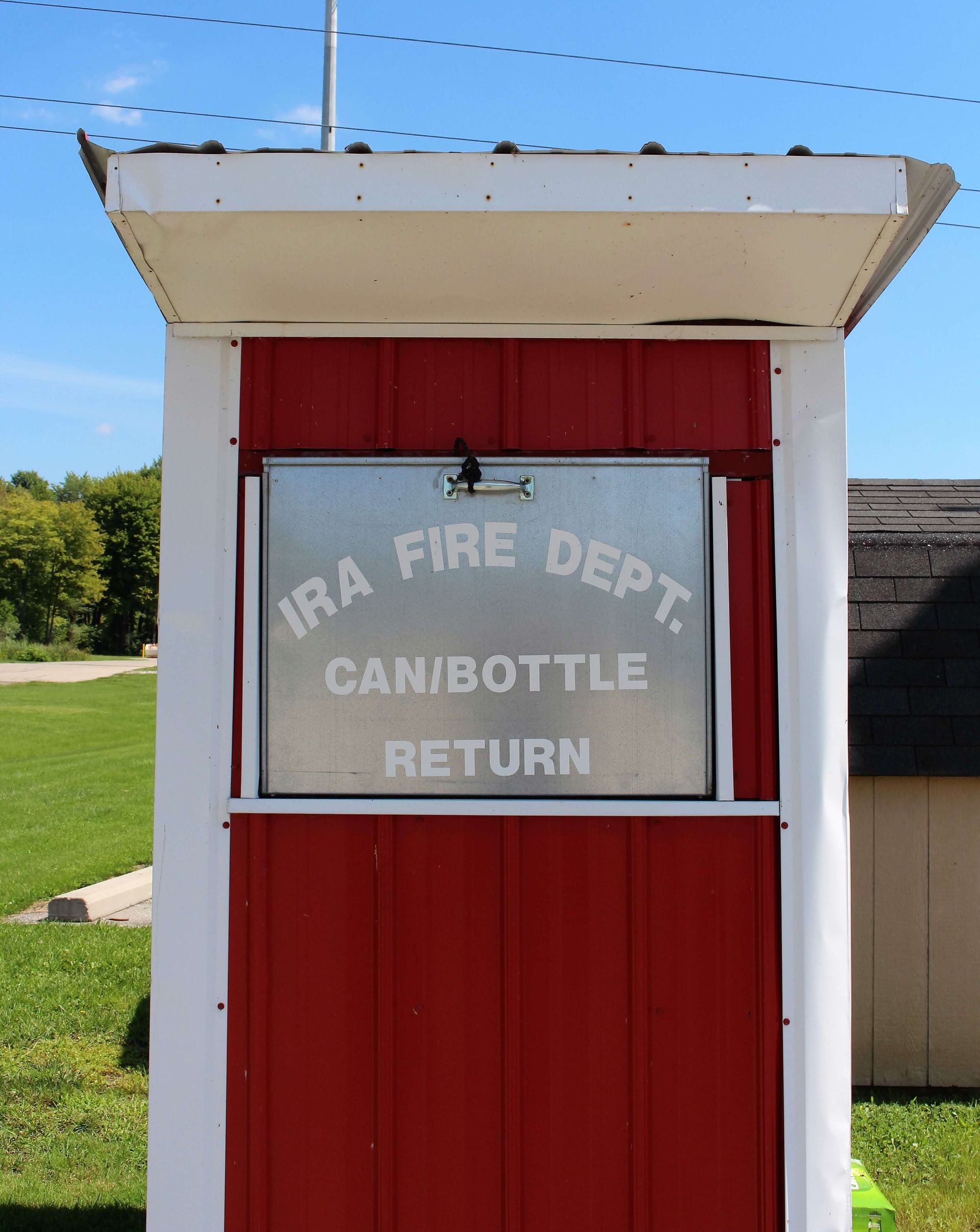 A red and white building with a sign that says Ira Fire Dept. Can/Bottle Return.