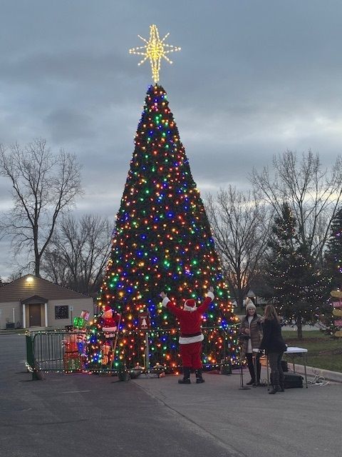 Santa claus is standing in front of a christmas tree.
