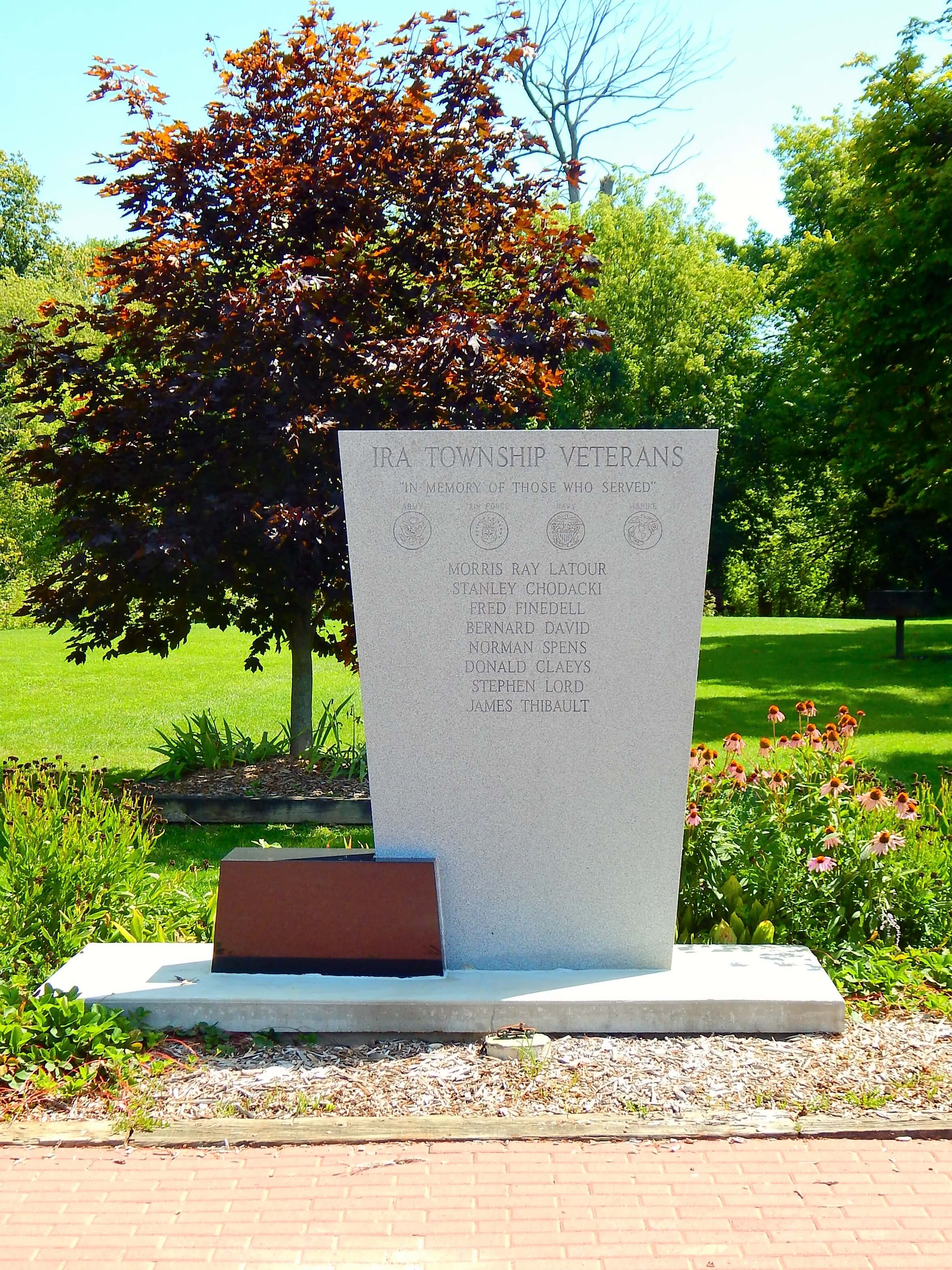 A memorial in a park with a tree in the background.