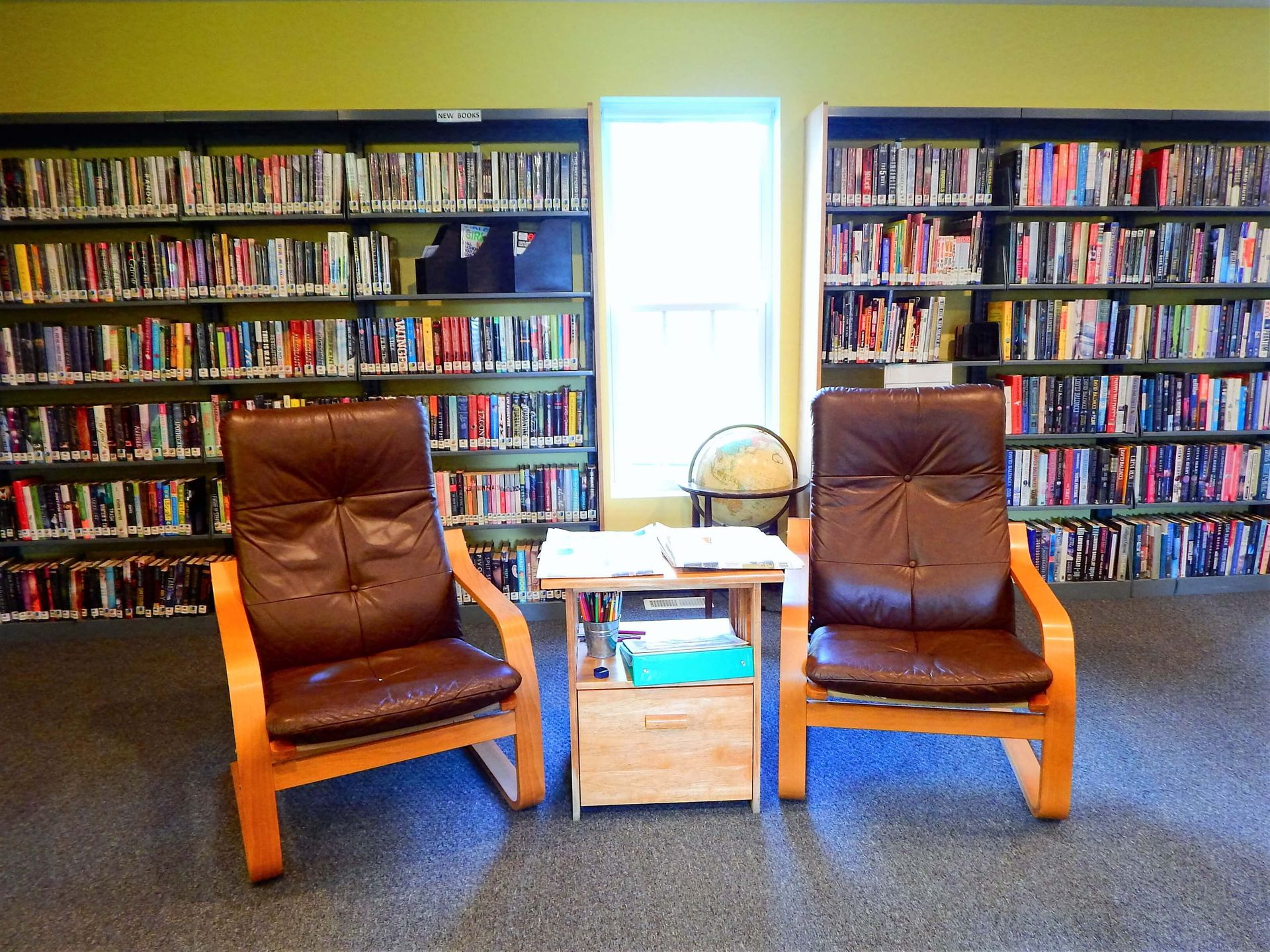 Two chairs sit in front of a bookshelf in a library.