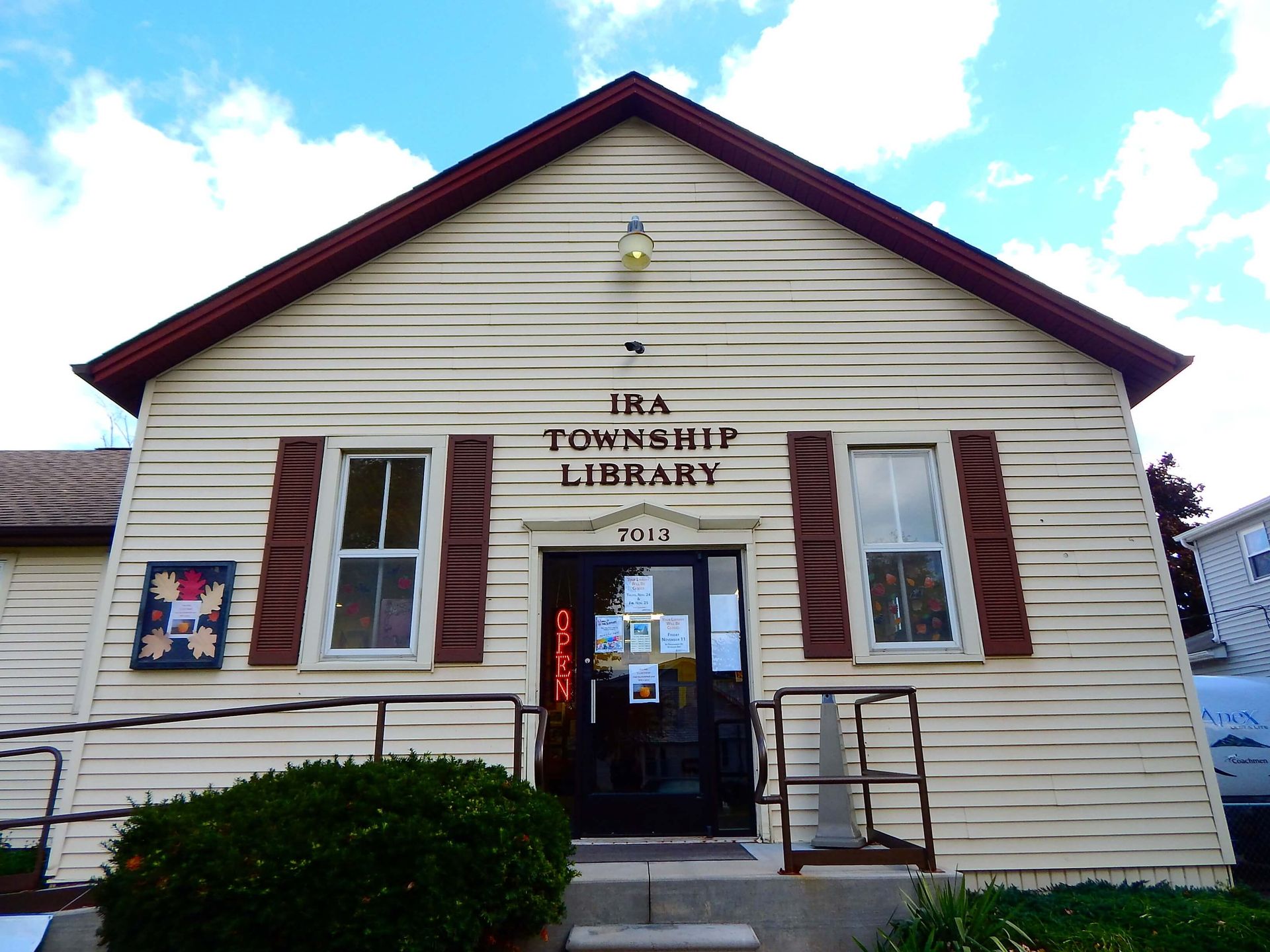 A white building with brown shutters that says Ira Township Library.