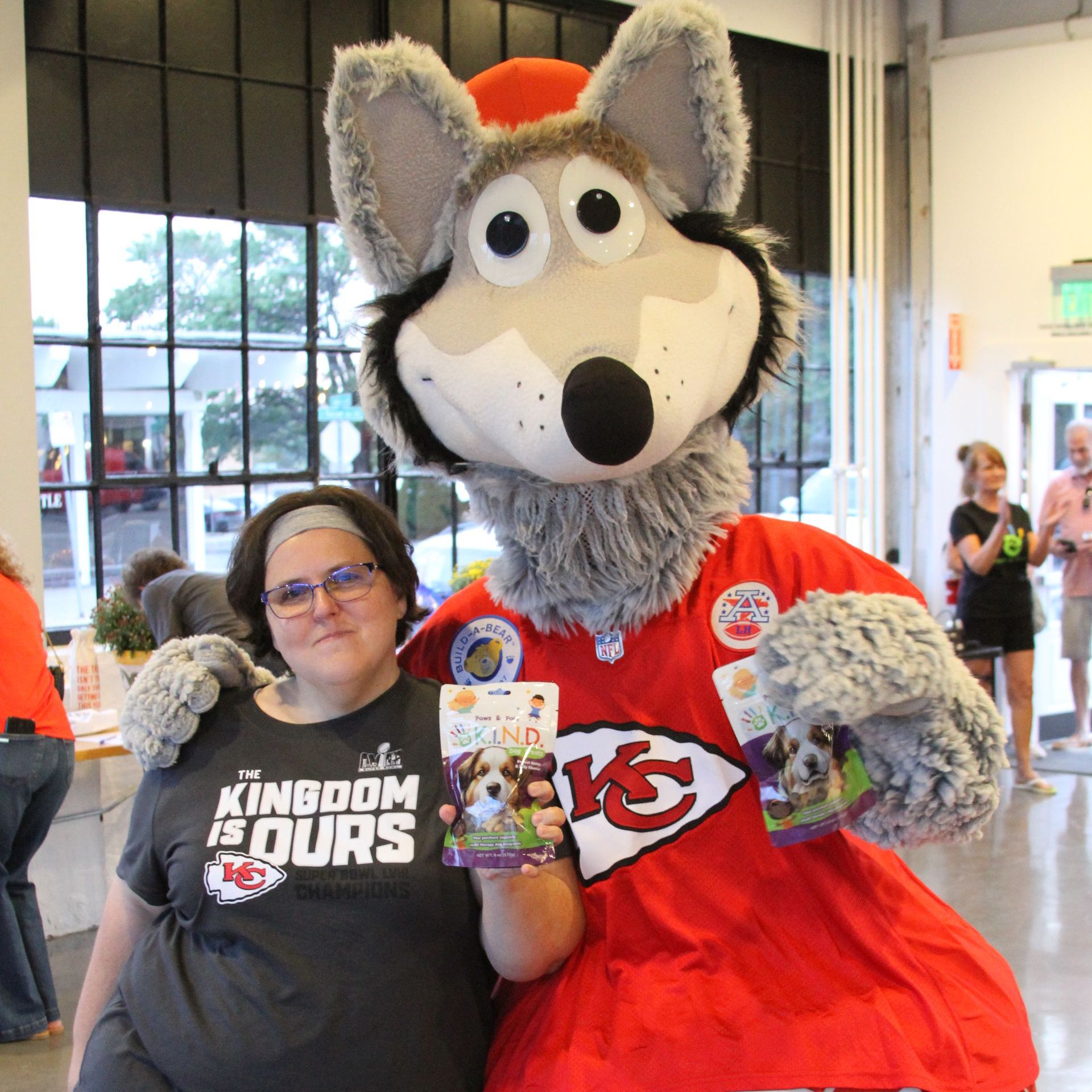 A woman wearing a kingdom is ours shirt poses with a mascot