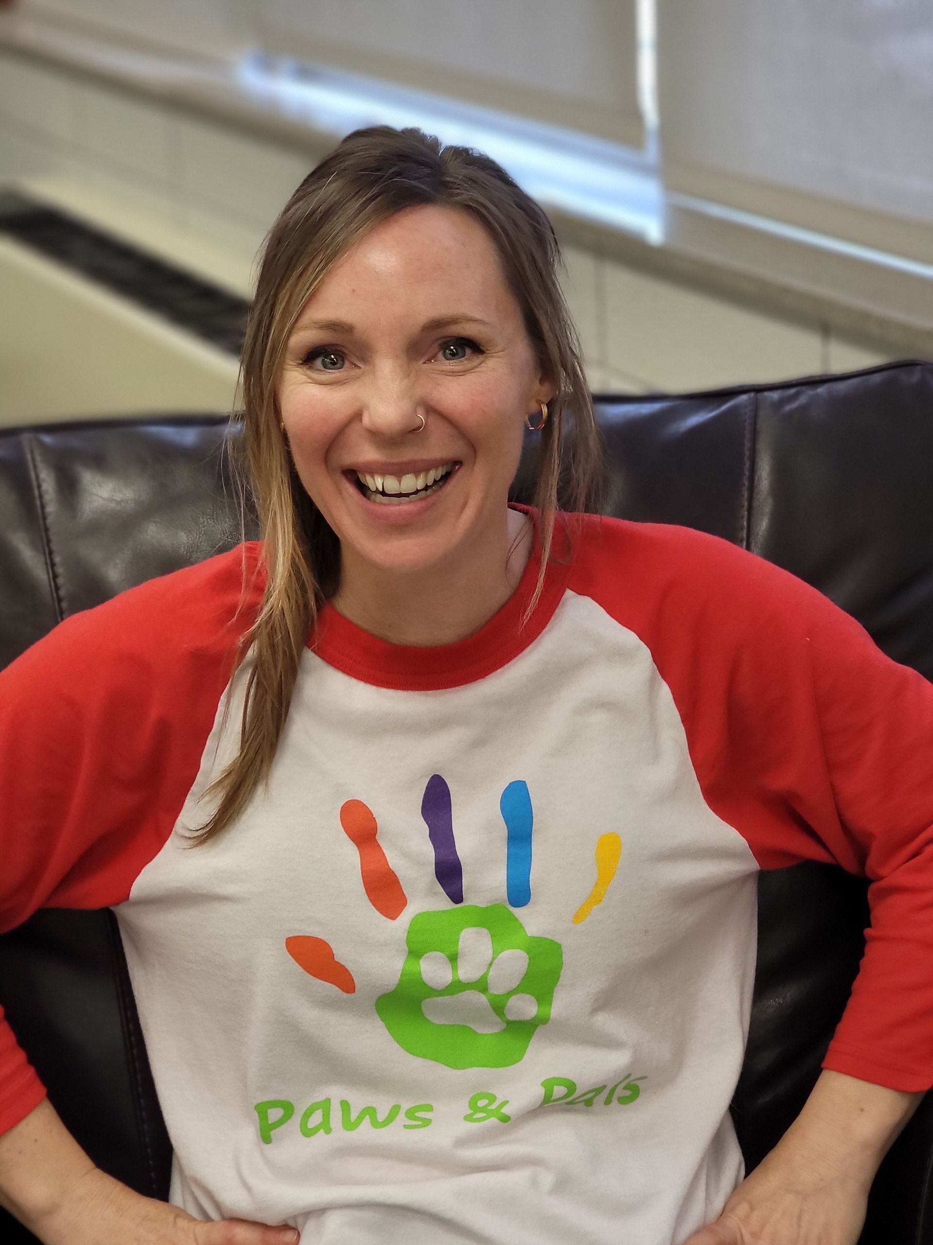 A woman is sitting on a couch wearing a paws and paws shirt