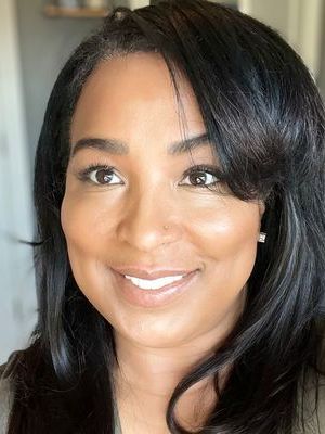 A woman with long black hair is smiling for the camera.