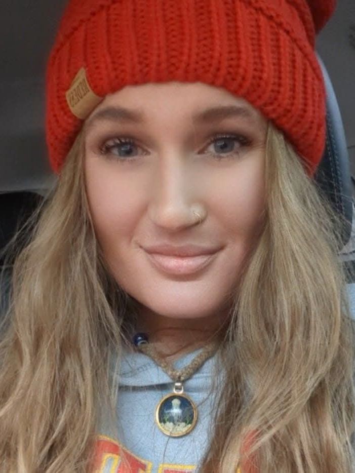 A woman wearing a red hat and a necklace is smiling for the camera.