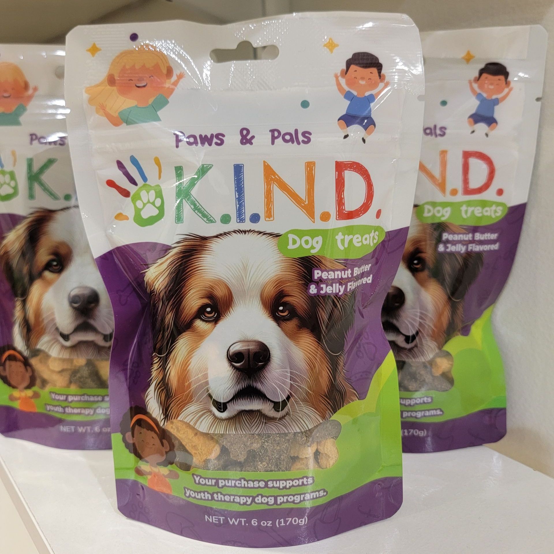 Three bags of kind dog treats are sitting on a shelf