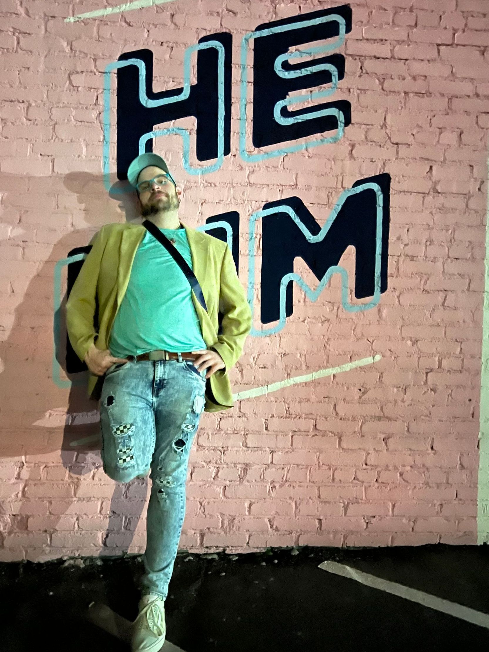 A man is standing in front of a pink brick wall.