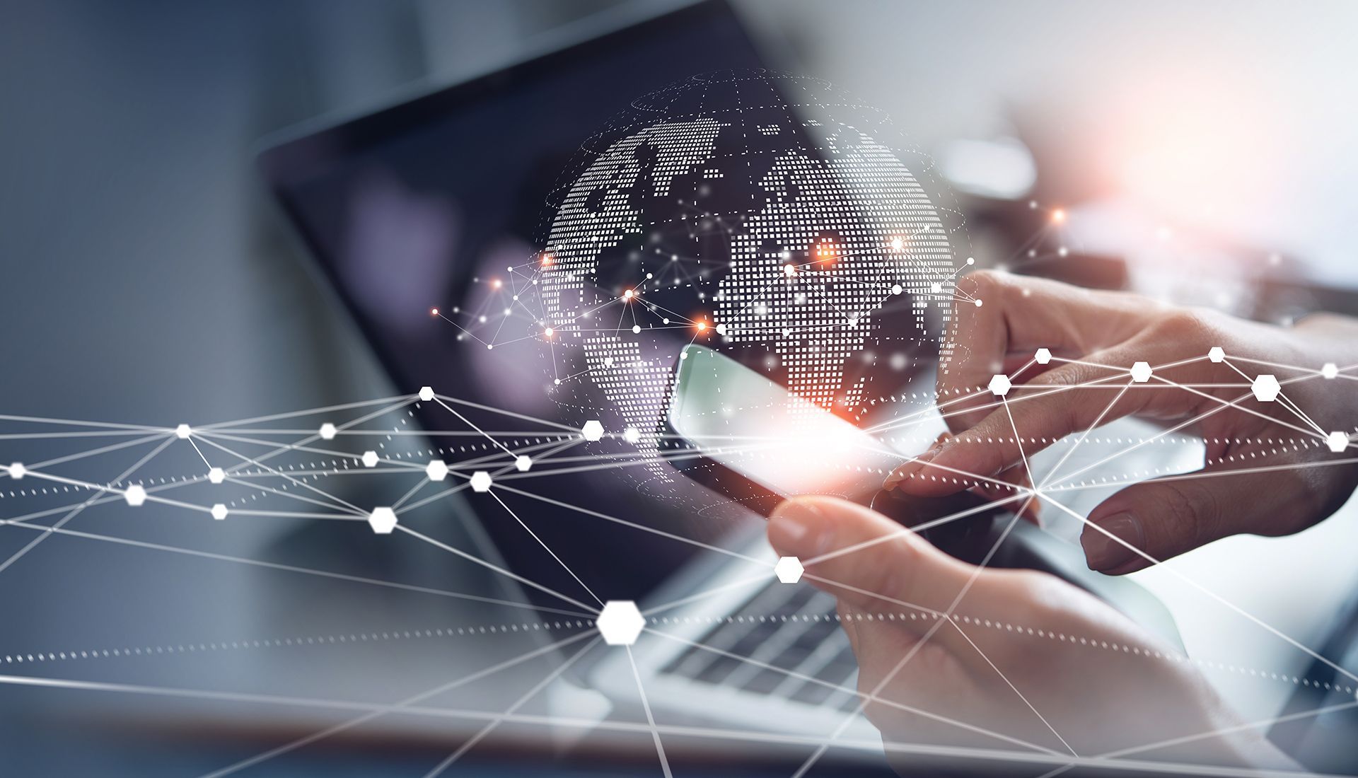 Person using smartphone and laptop with a digital globe overlay and network lines.