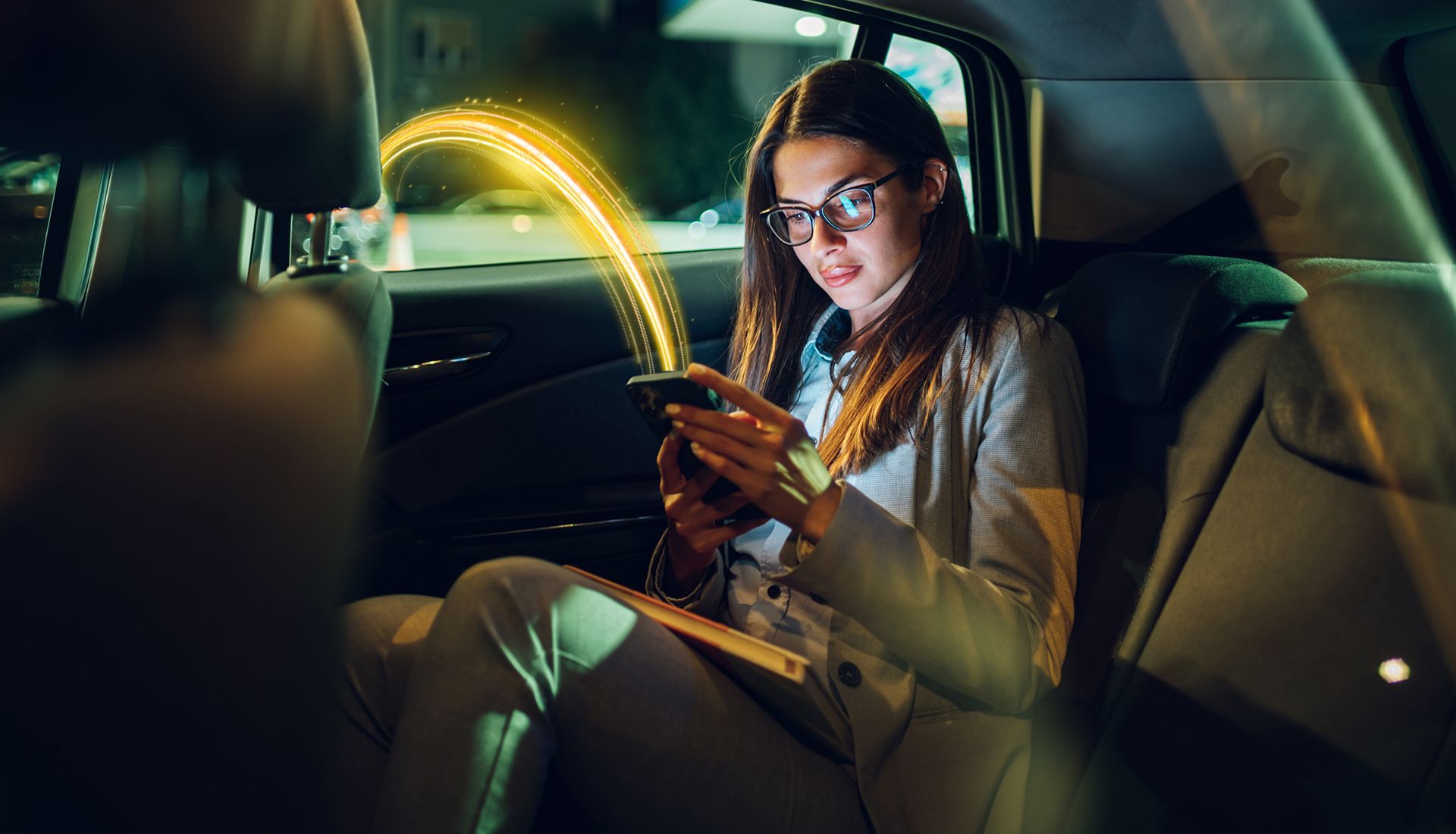 Woman in glasses using phone in a car, with a glowing line connecting phone. Nighttime setting.