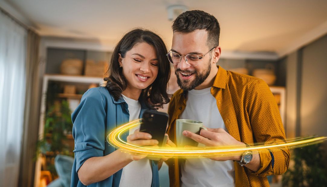 Couple looking at phone, glowing yellow line around it, smiling in home setting.