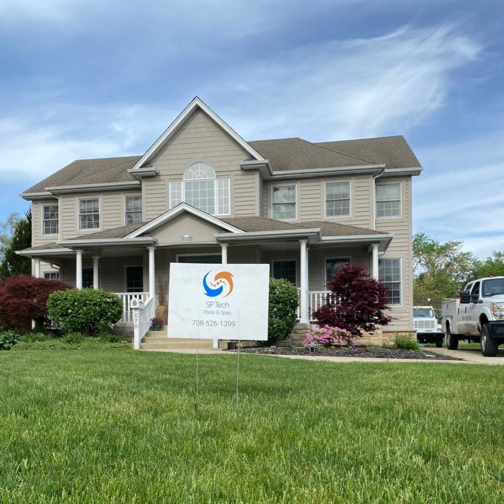 Two-story house with sign for on the lawn. Green grass, cloudy sky, white truck.