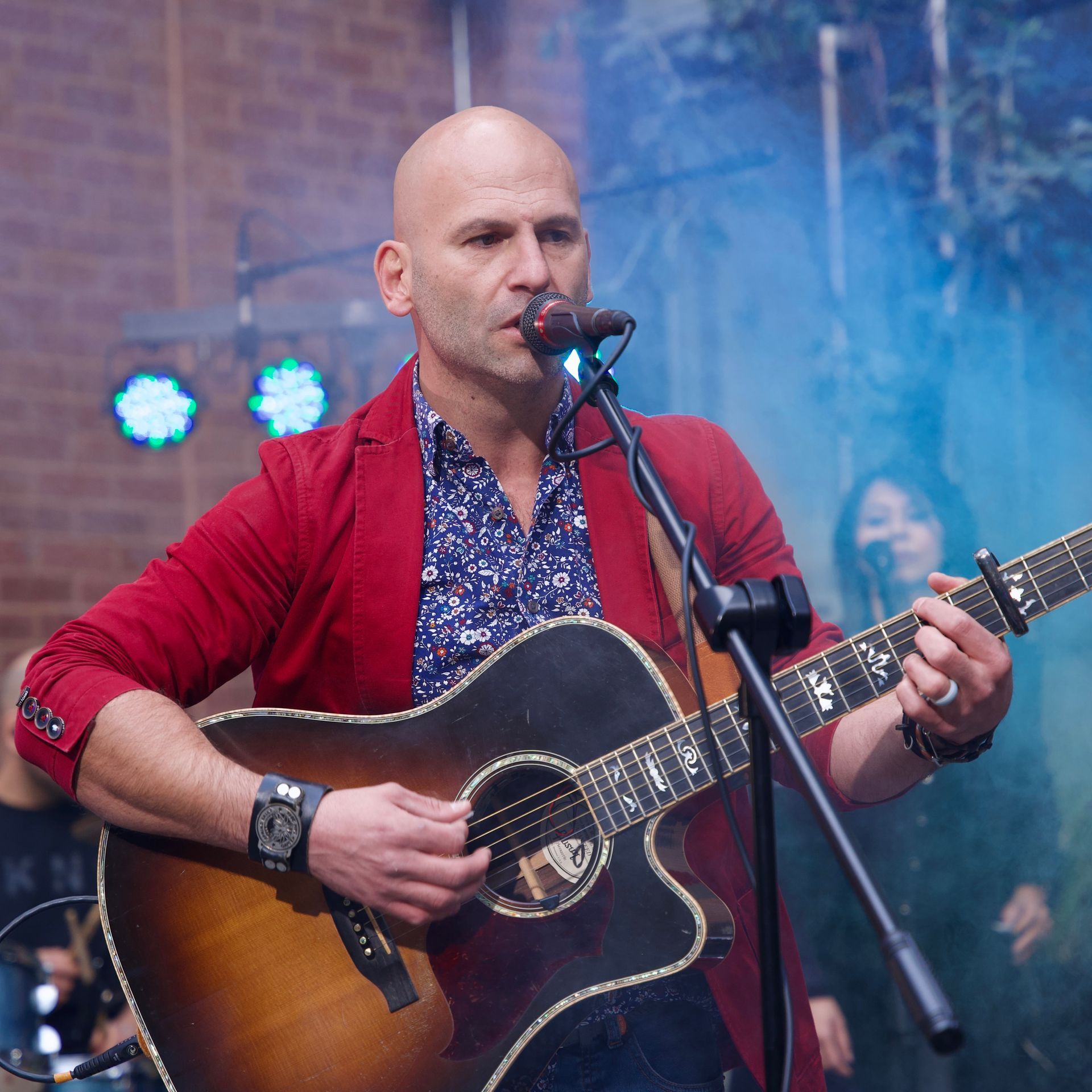 A man singing into a microphone while holding a guitar