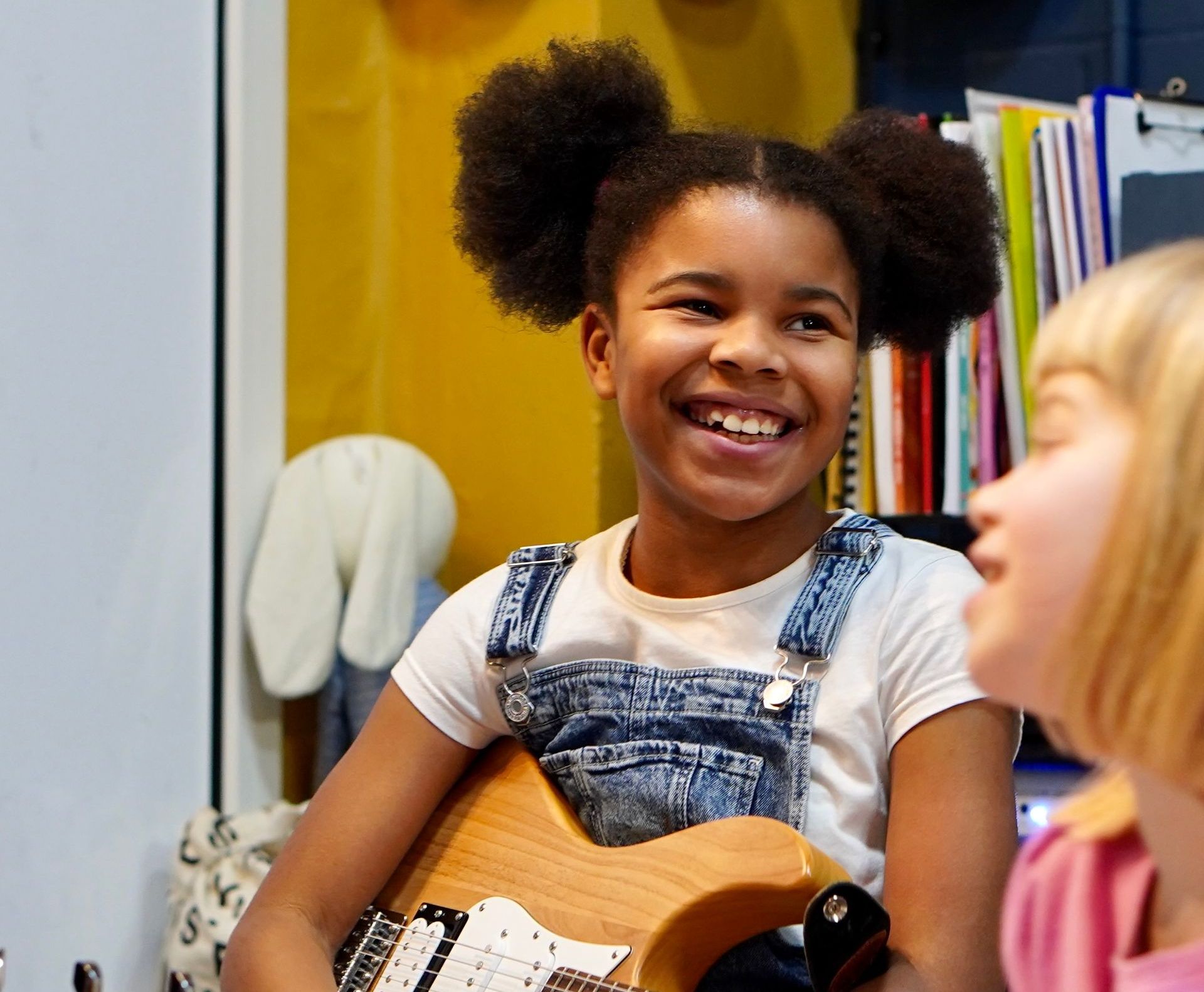 A young girl is holding a guitar and smiling