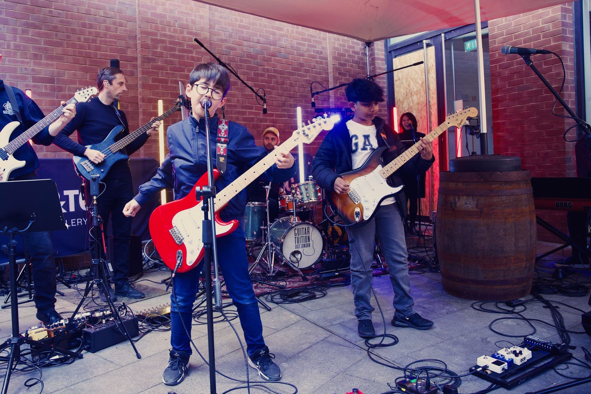 A group of people are playing guitars and singing into microphones on a stage.