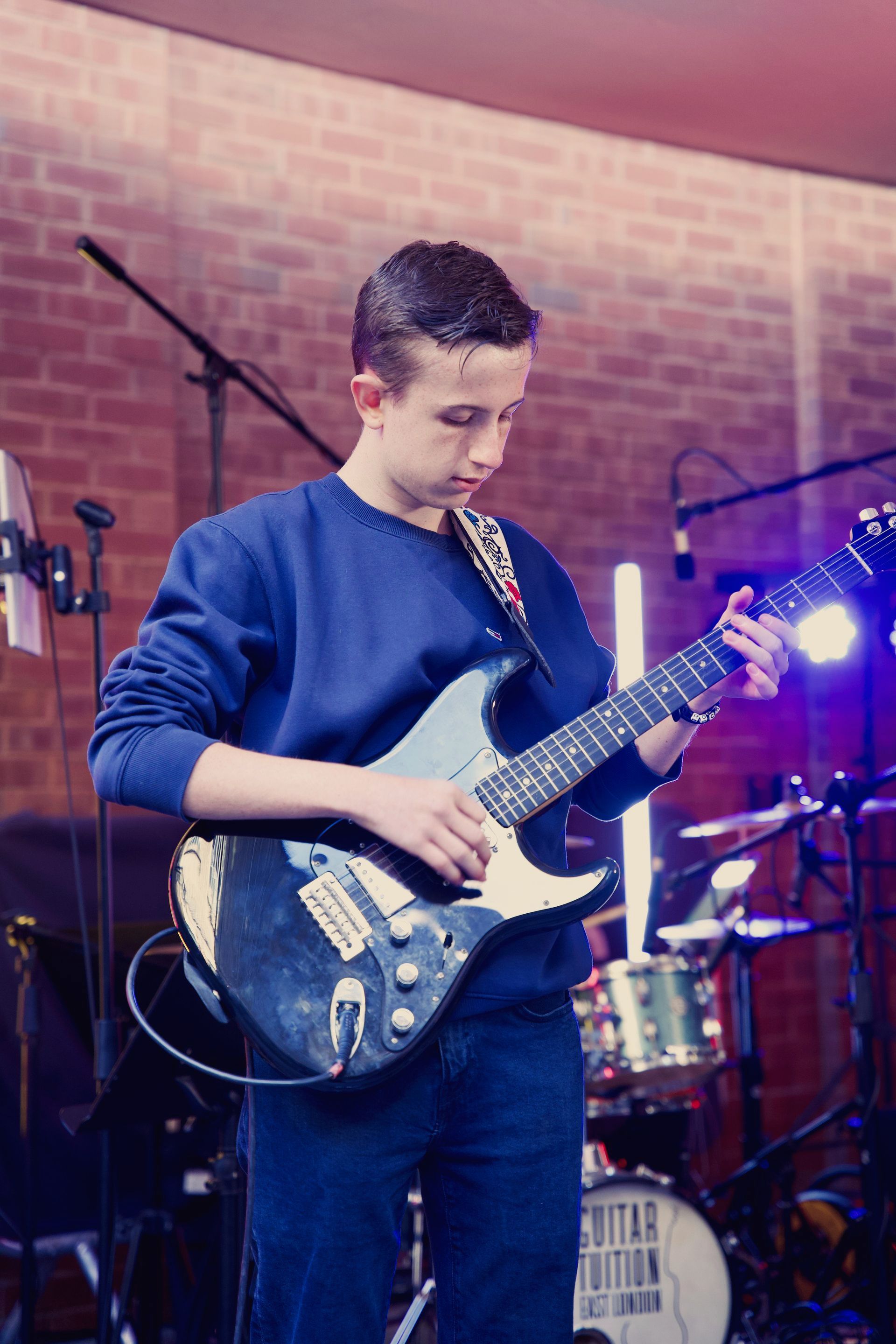 A young man is playing an electric guitar on a stage.