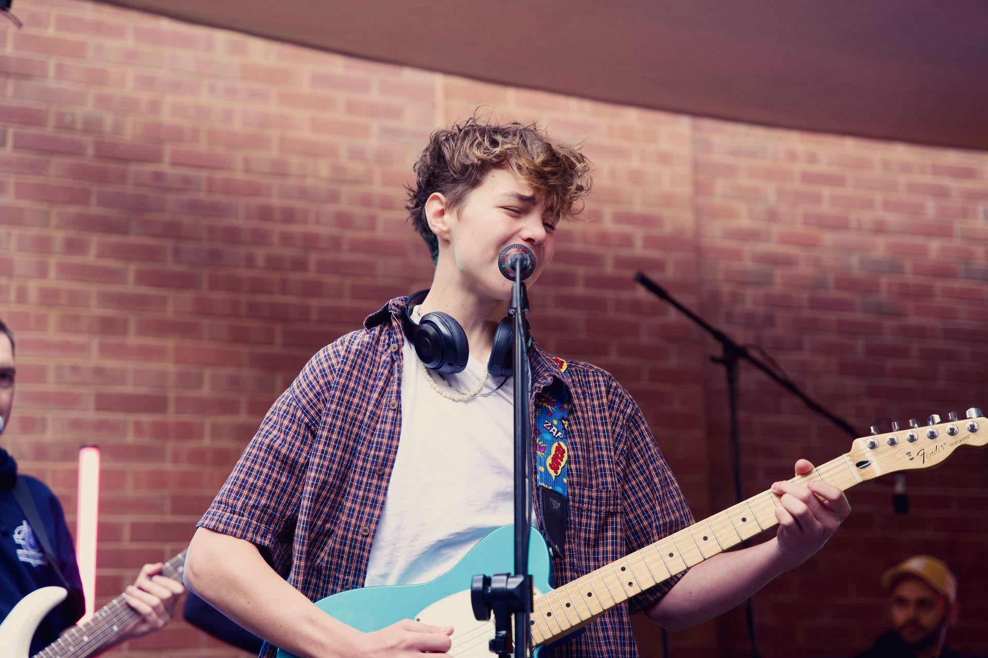 A young man is playing a guitar and singing into a microphone.