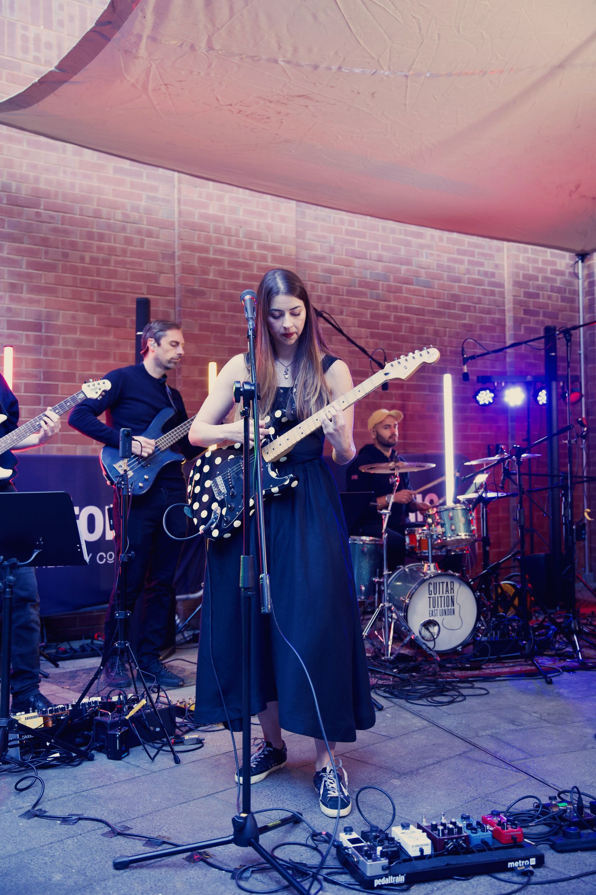 A woman is playing a guitar on stage with a band.