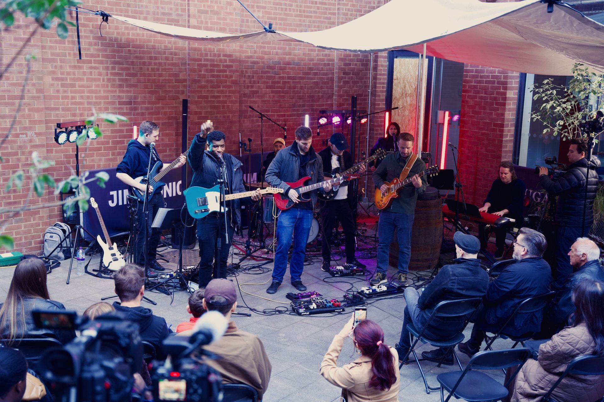 A group of people are sitting in chairs watching a band perform on stage.